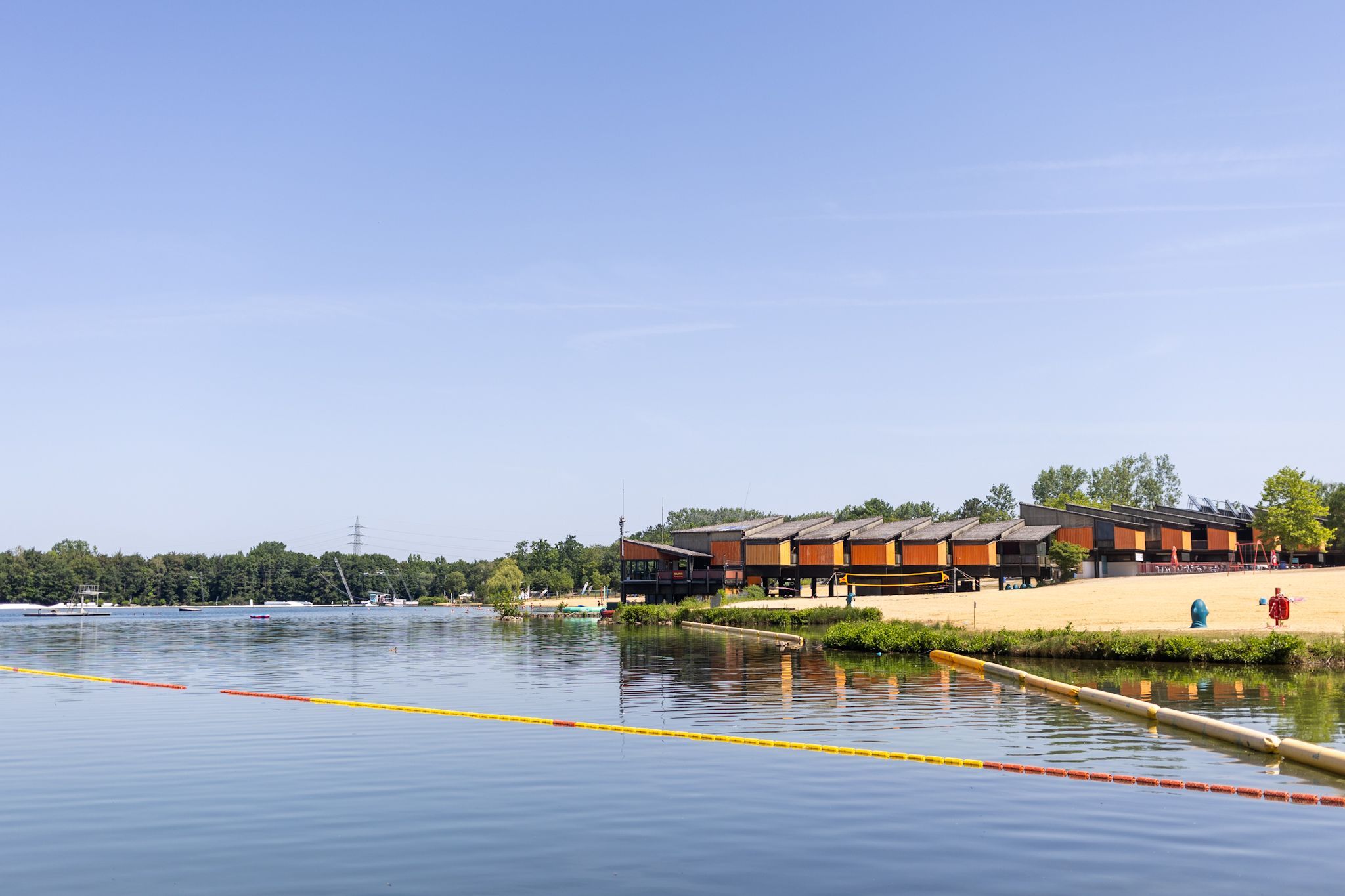 Blick auf den See und einen Steg mit orangefarbenen Häuschen obendrauf.