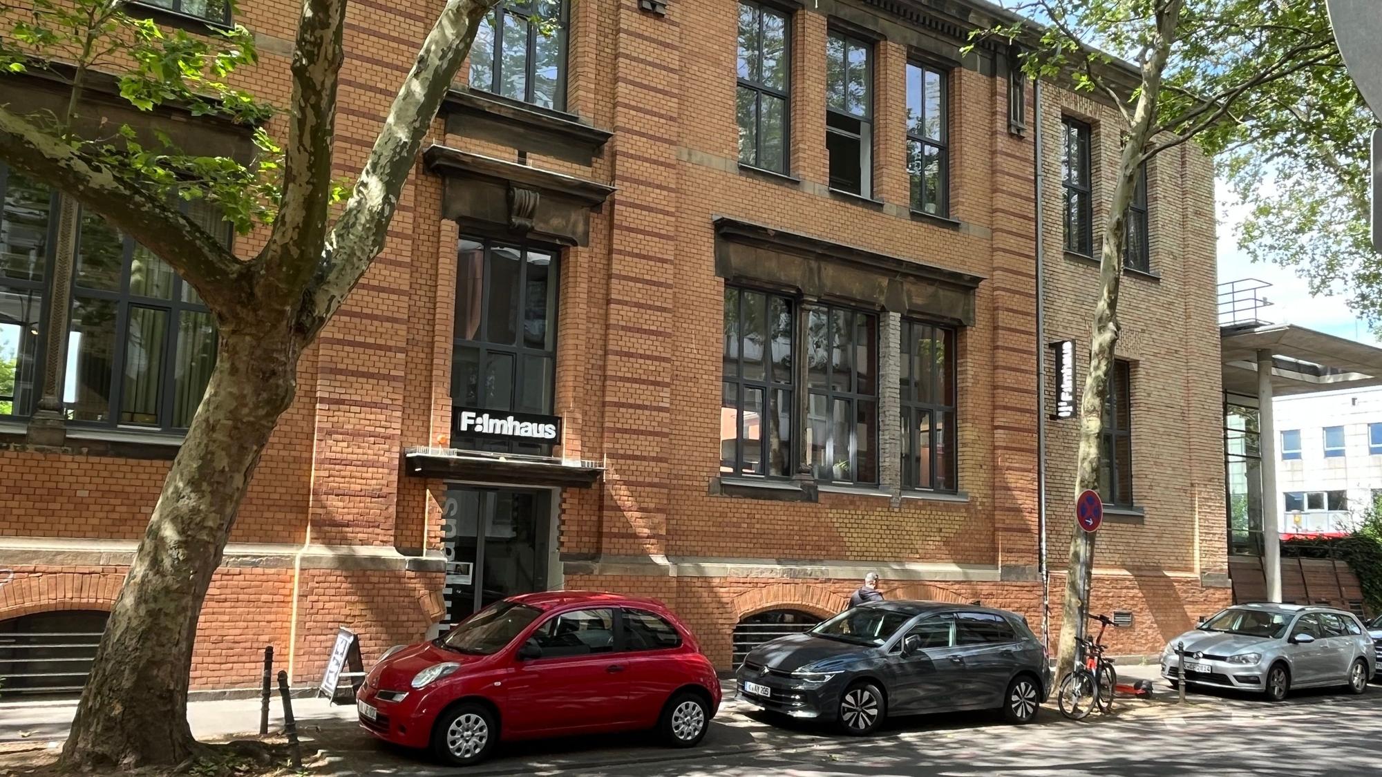 Ein Backsteingebäude mit dem Schriftzug „Filmhaus“ über dem Eingang steht an einer Straße.