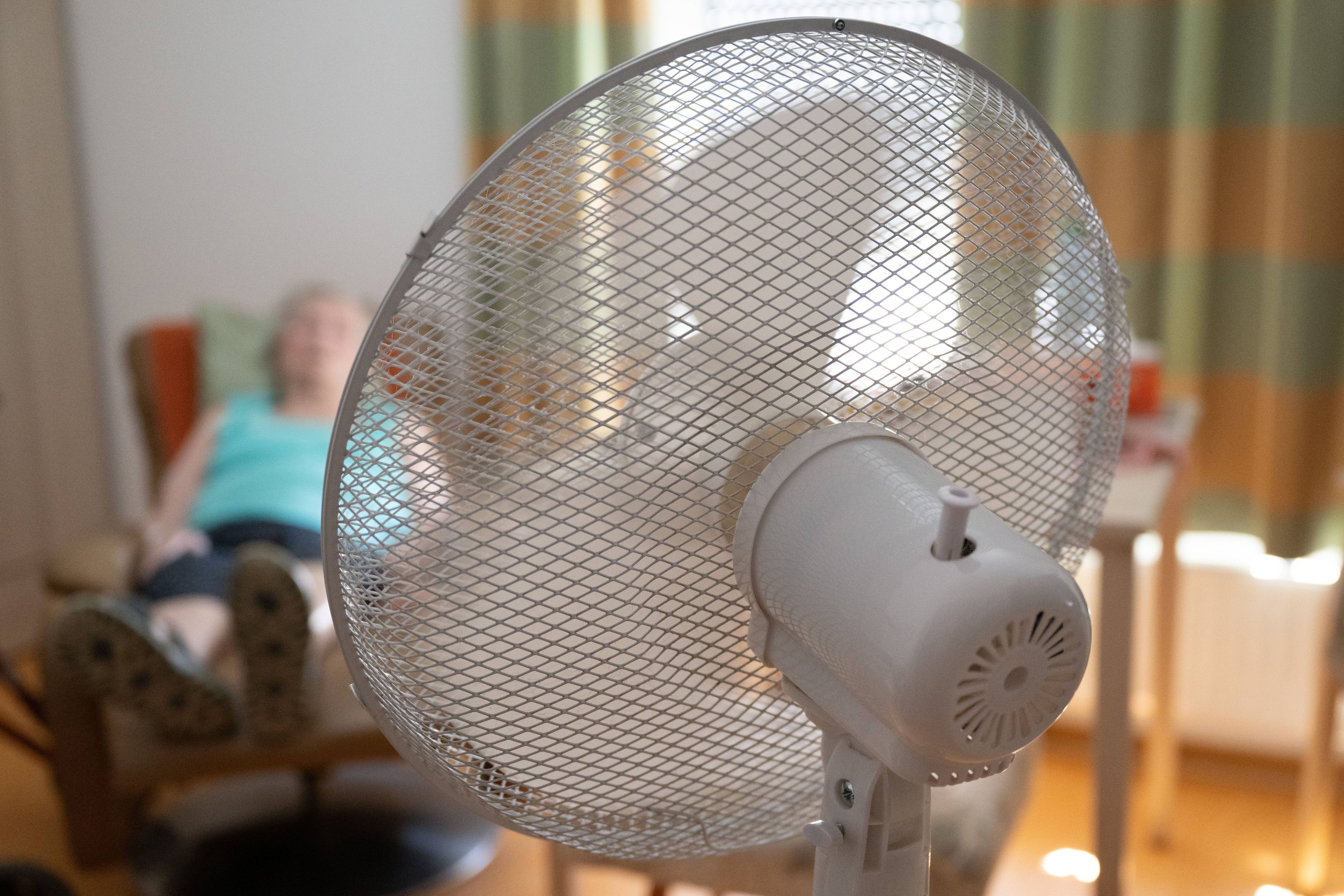 Die Bewohnerin eines Seniorenzentrums sitzt in ihrem Zimmer hinter einem Ventilator in einem Sessel.