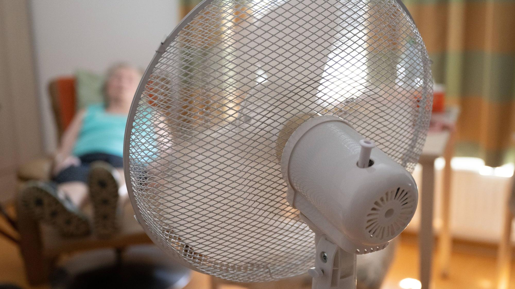 Die Bewohnerin eines Seniorenzentrums sitzt in ihrem Zimmer hinter einem Ventilator in einem Sessel.