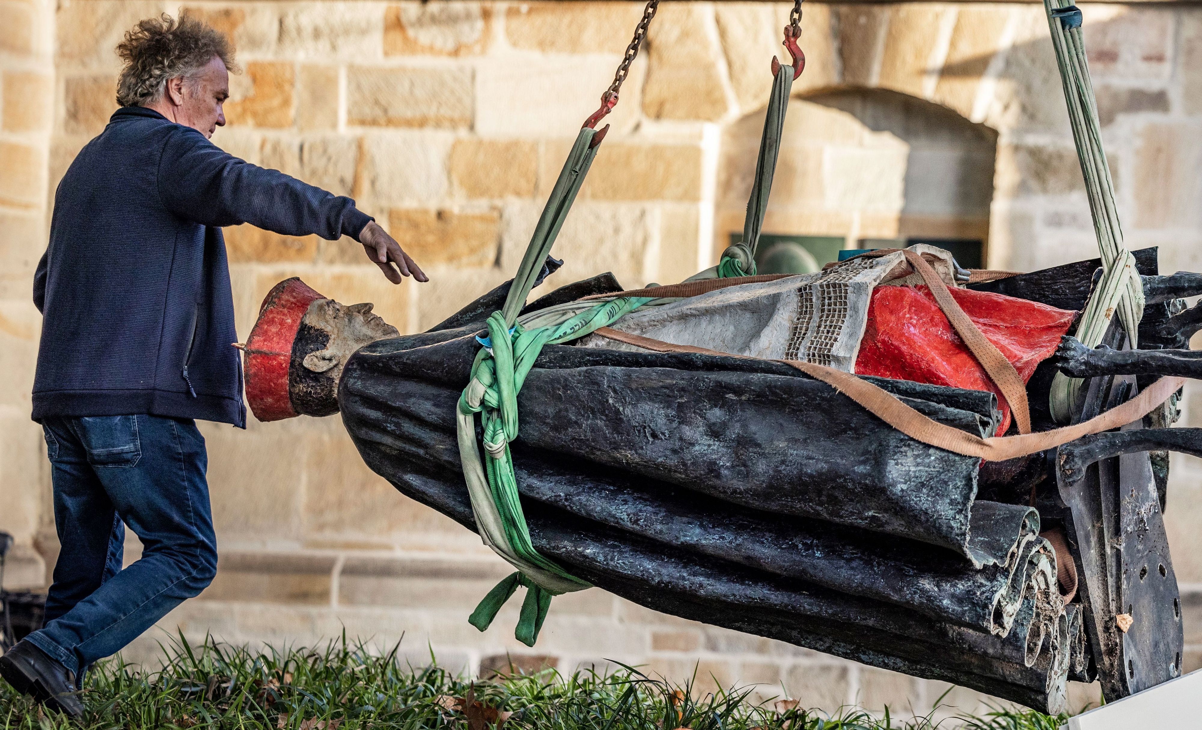 25.09.2023, Nordrhein-Westfalen, Essen: Die Skulptur des Essener Kardinals Franz Hengsbach hängt nach der Demontage vor dem Essener Dom an einem Kran und wird verladen. Das Bistum Essen hatte mitgeteilt, dass der «gravierende» Verdacht bestehe, Hengsbach könnte in seiner Zeit als Weihbischof in Paderborn eine 16-Jährige sexuell missbraucht haben.