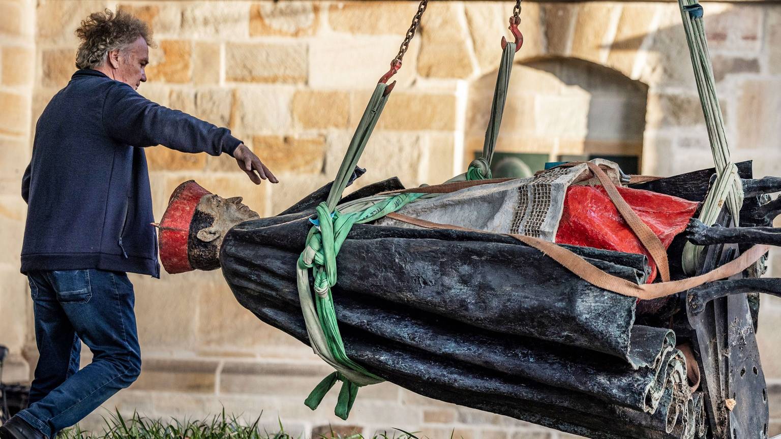 25.09.2023, Nordrhein-Westfalen, Essen: Die Skulptur des Essener Kardinals Franz Hengsbach hängt nach der Demontage vor dem Essener Dom an einem Kran und wird verladen. Das Bistum Essen hatte mitgeteilt, dass der «gravierende» Verdacht bestehe, Hengsbach könnte in seiner Zeit als Weihbischof in Paderborn eine 16-Jährige sexuell missbraucht haben.