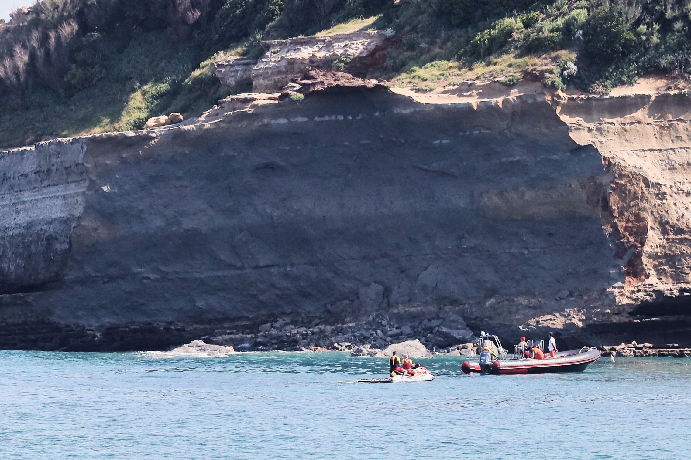Rettungskräfte suchen von Booten aus nach einer vermissten Person in der Nähe eines riesigen Küstenabschnitts. Am Mittwochabend ist ein großer Felsen von einer Steilküste abgebrochen und ins Meer gestürzt, wobei ein Taucher ums Leben kam und ein weiterer vermisst wird.