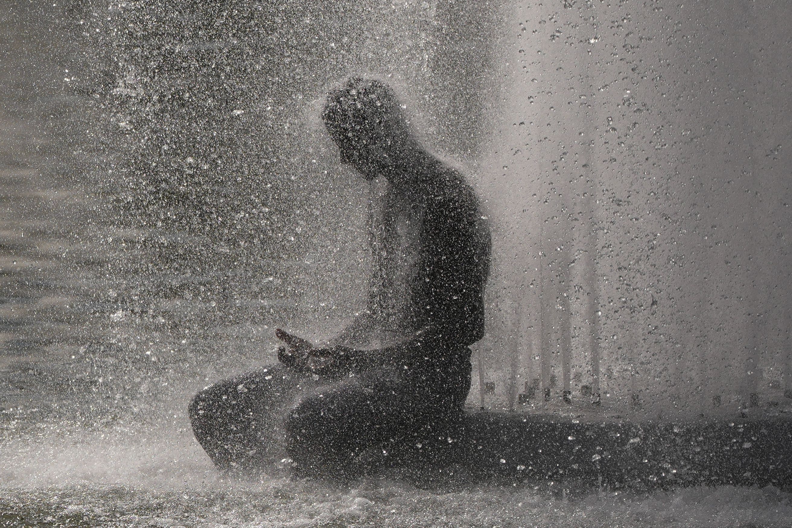 Eine Person erfrischt sich während einer Hitzewelle in Paris an der Fontaine de Varsovie in der Nähe des Eiffelturms.