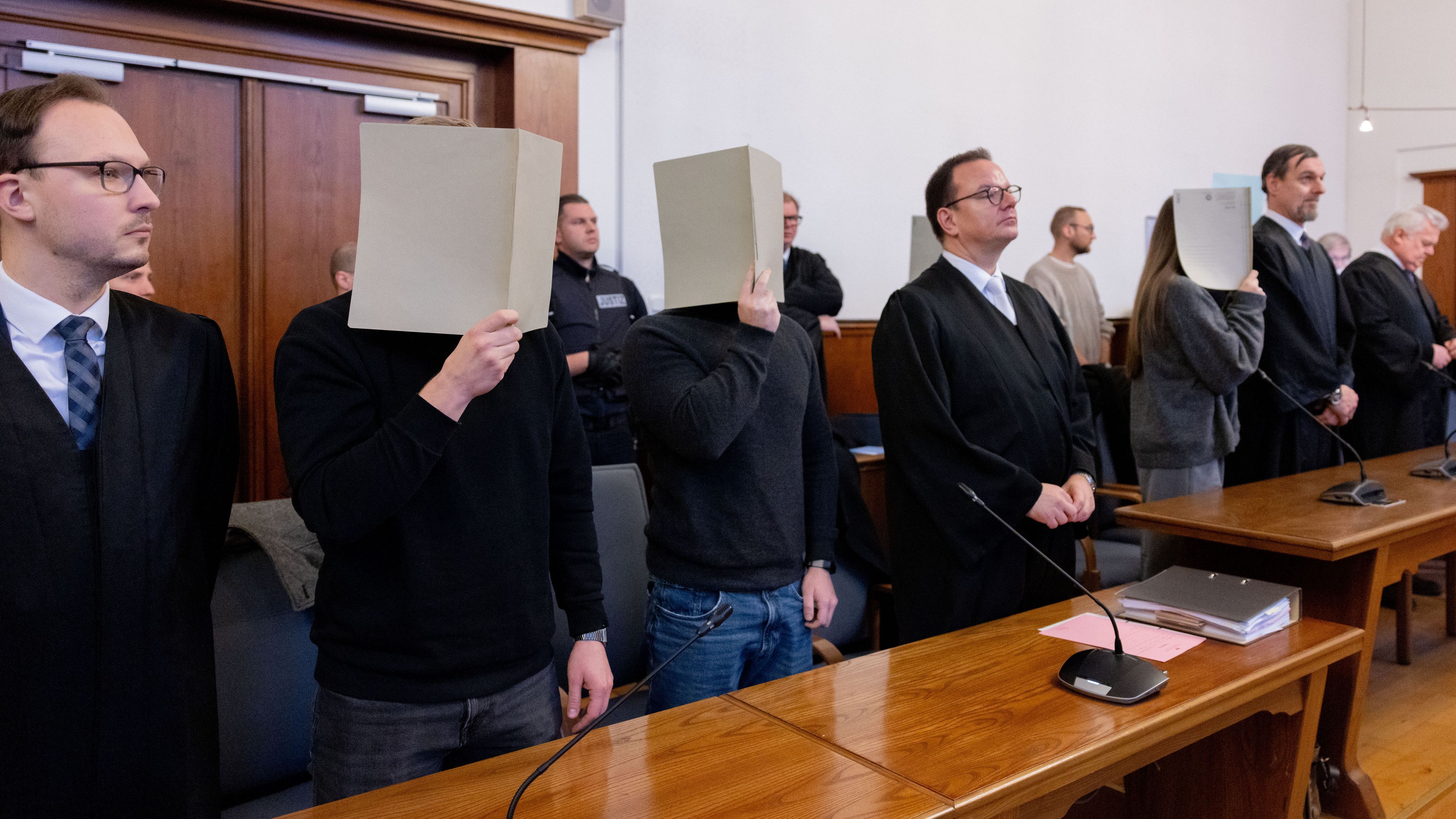 Die fünf angeklagten Polizeibeamtinnen und -beamten erheben sich im Gerichtssaal des Landgerichts. Im Prozess um tödliche Schüsse auf einen 16-jährigen Flüchtling werden die Urteile erwartet. +++ dpa-Bildfunk +++