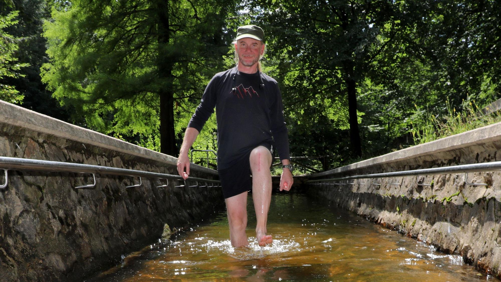 Ein Mann läuft durch eine Wassertretstelle im Königsforst.