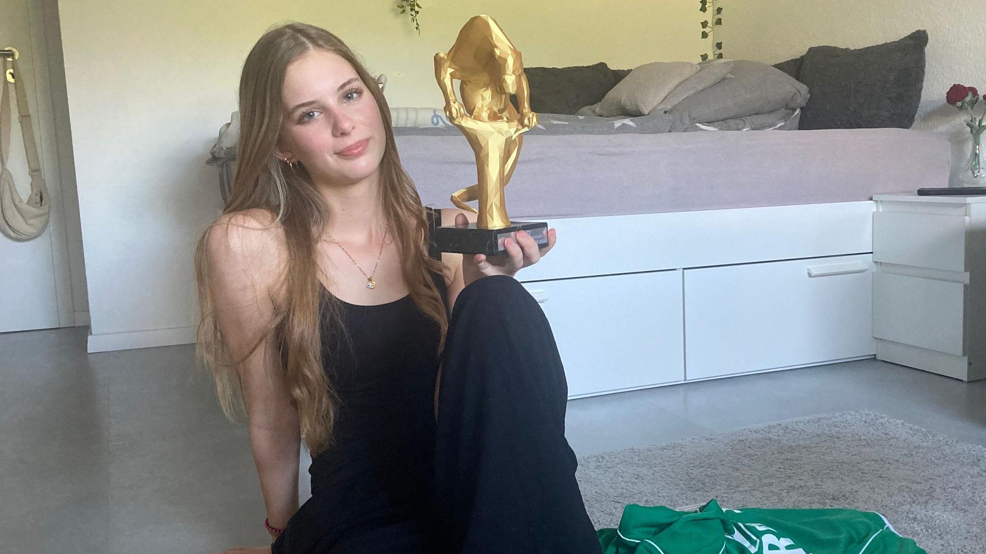 Zu sehen ist die Poetry-Slammerin Hannah Breitbarth mit einem Pokal in der Hand.