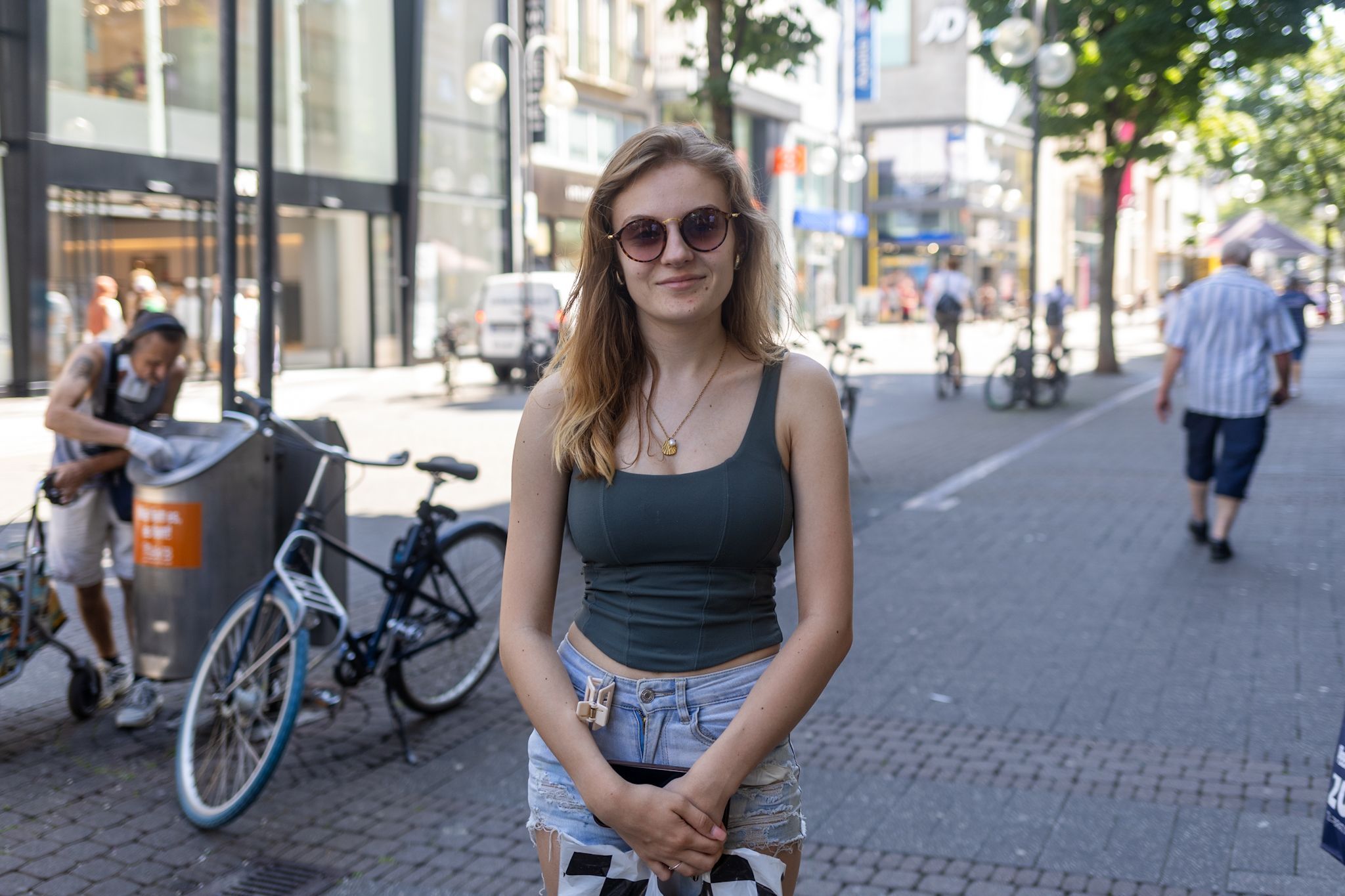 Eine junge Frau mit Sonnenbrille lächelt in die Kamera.