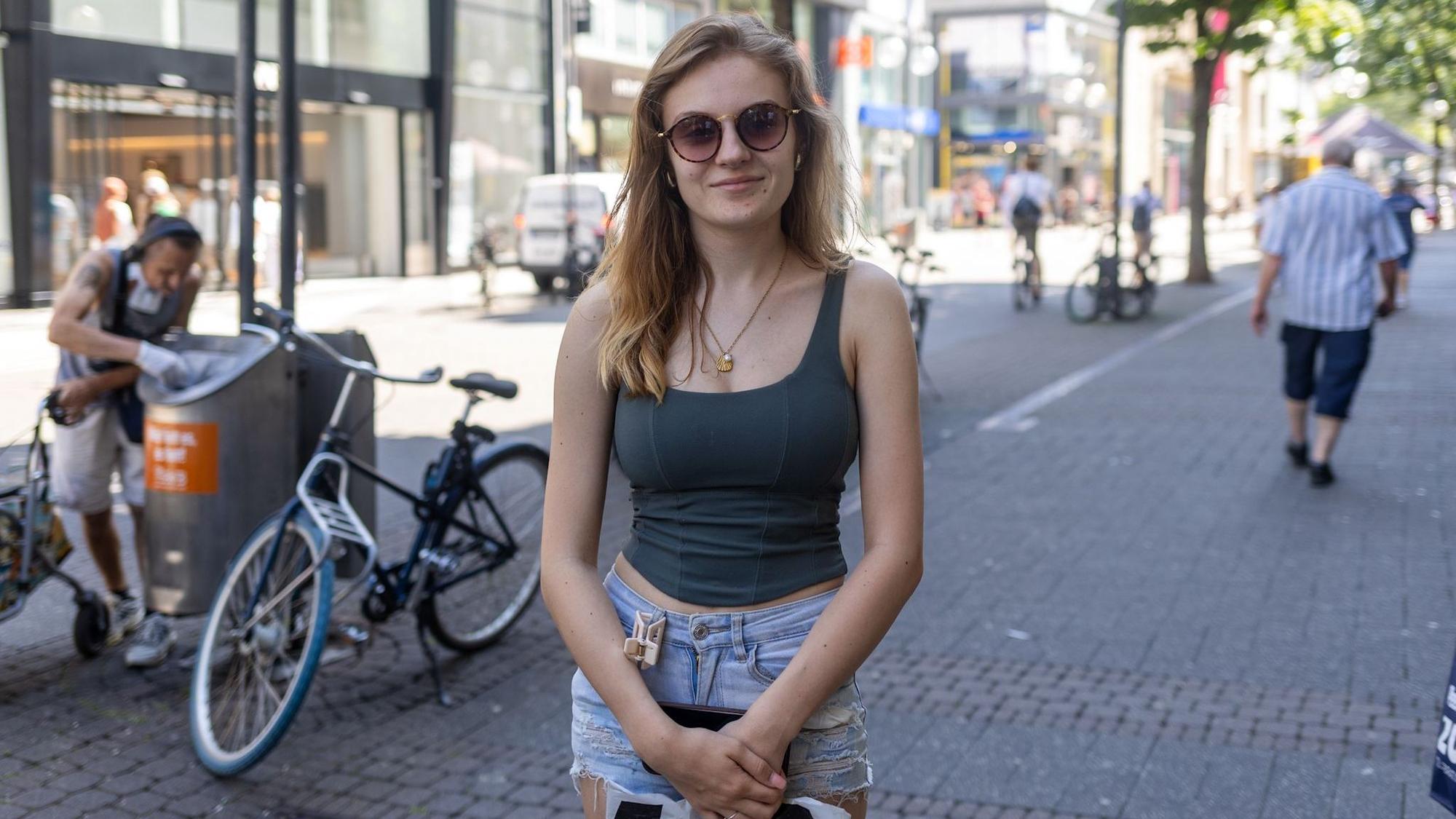 Eine junge Frau mit Sonnenbrille lächelt in die Kamera.