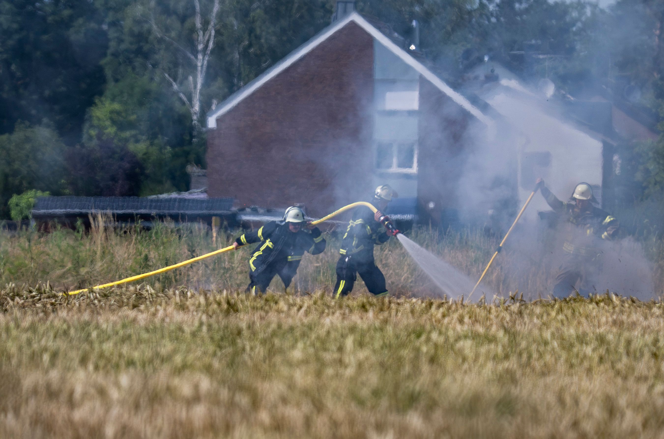 Feuerwehrkräfte löschen einen Brand auf einem Feld.