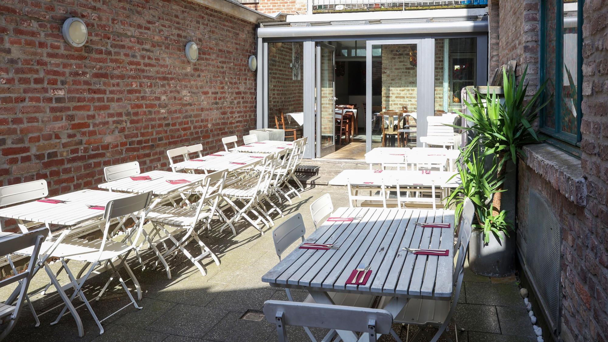 Die Terrasse im Innenhof mit weißen Gartenmöbeln ist zu sehen.