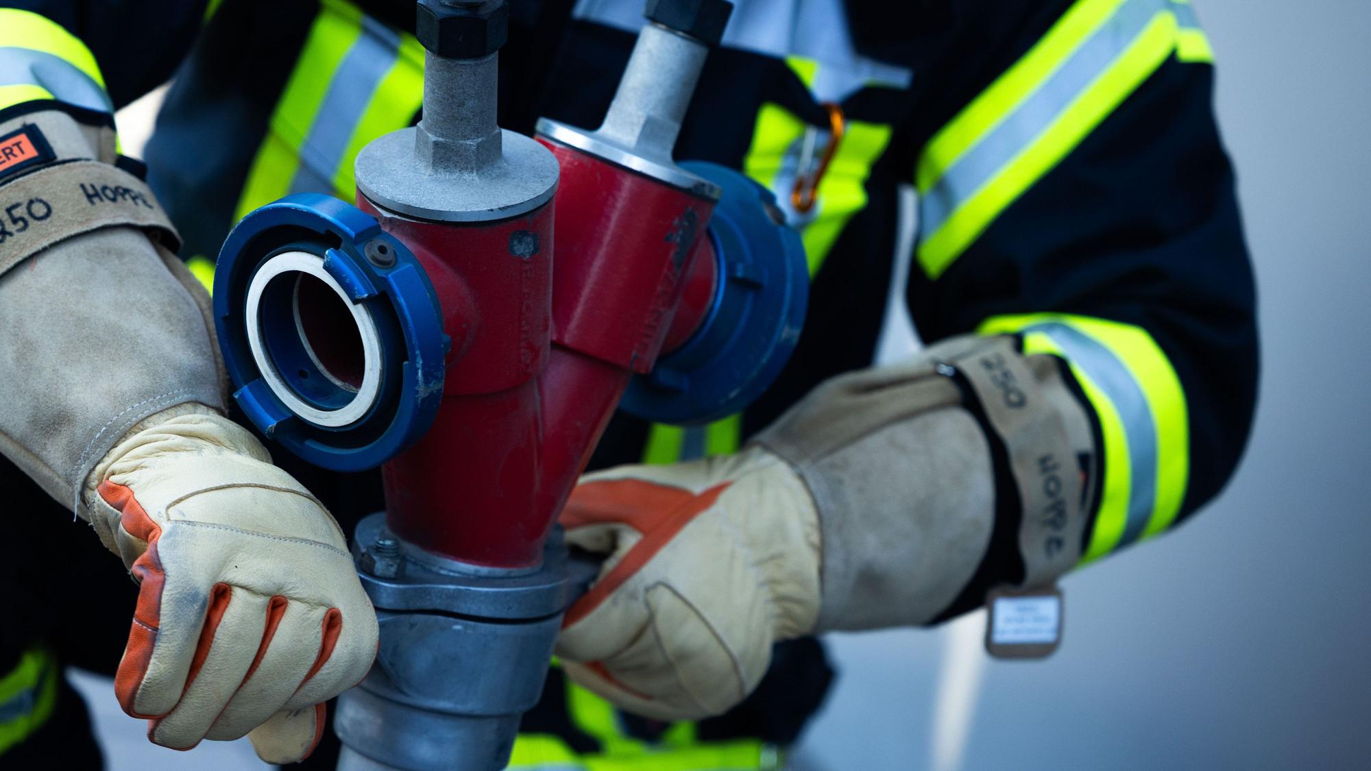 Ein Feuerwehrmann montiert einen Schlauch.