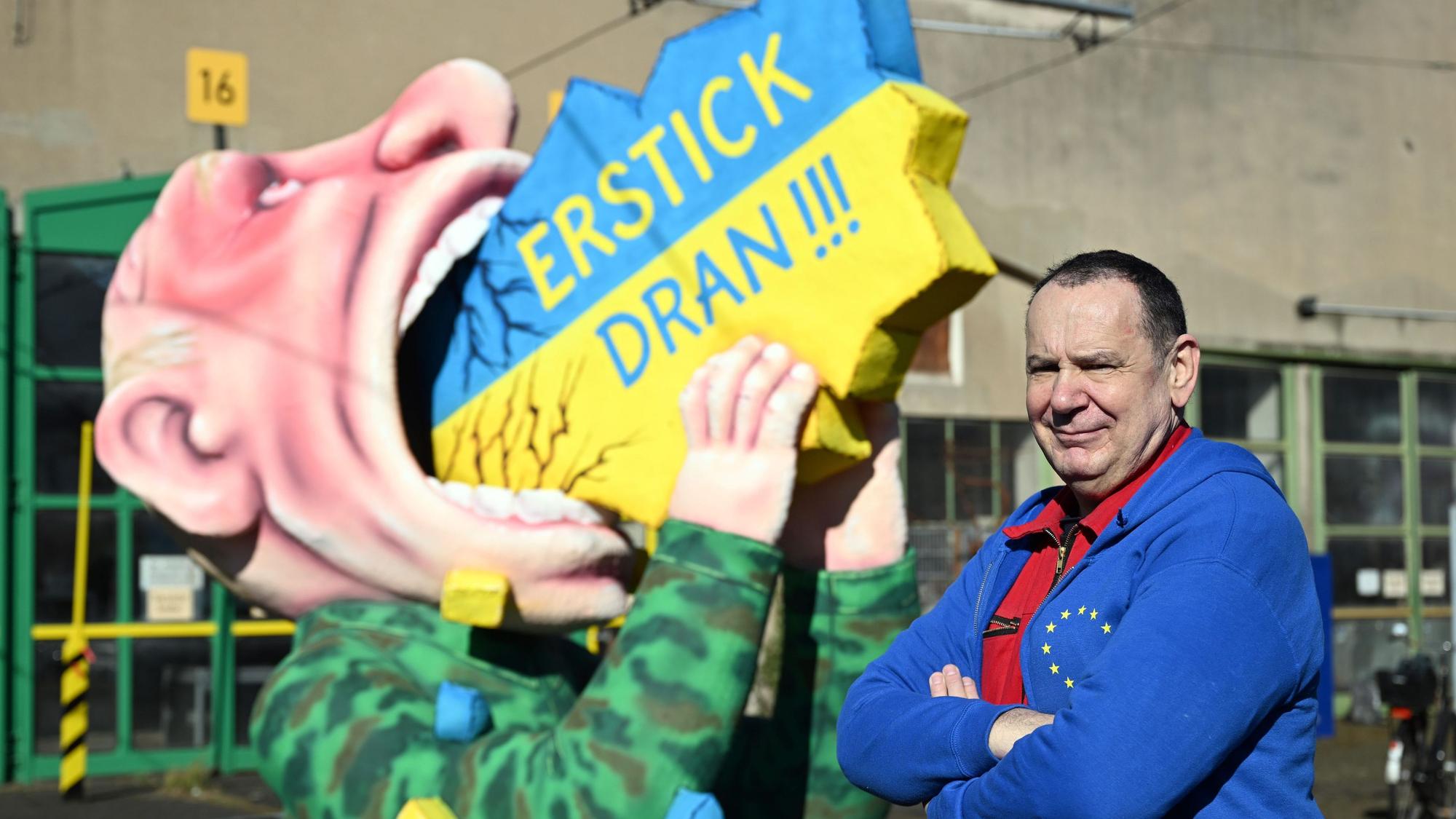 Jacques Tilly steht im Jahr 2022 vor einem Motivwagen mit dem russischen Präsidenten Putin, der die Ukraine schluckt.