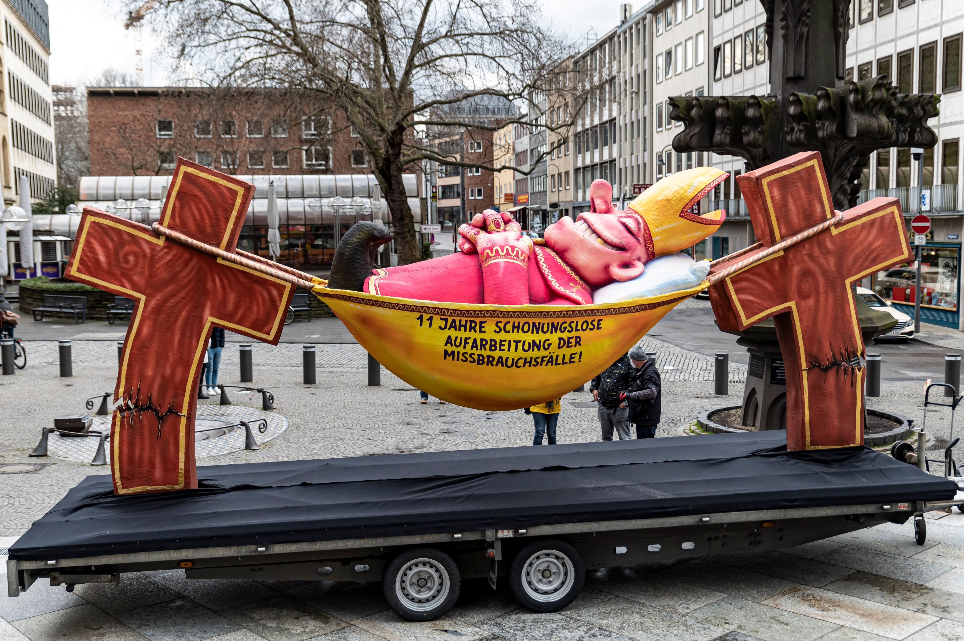 Die Plastik des Düsseldorfer Künstlers Jacques Tilly mit dem Slogan „11 Jahre schonungslose Aufarbeitung der Missbrauchsfälle" steht im März 2021 vor dem Kölner Dom in der Kölner Altstadt.