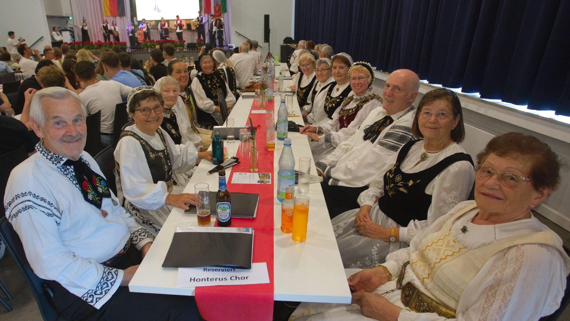 Leute in Tracht sitzen an einem langen Tisch.