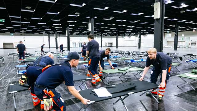 Helfer bauen das Notfallversorgungszentrum in einer Messehalle auf.