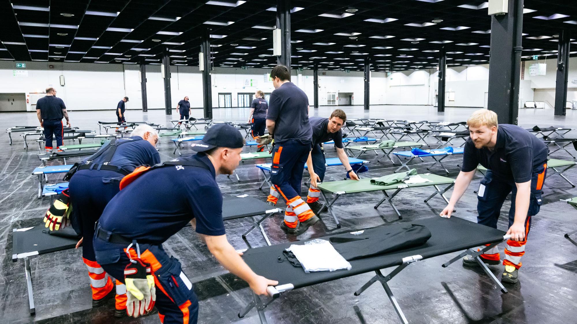 Helfer bauen das Notfallversorgungszentrum in einer Messehalle auf.