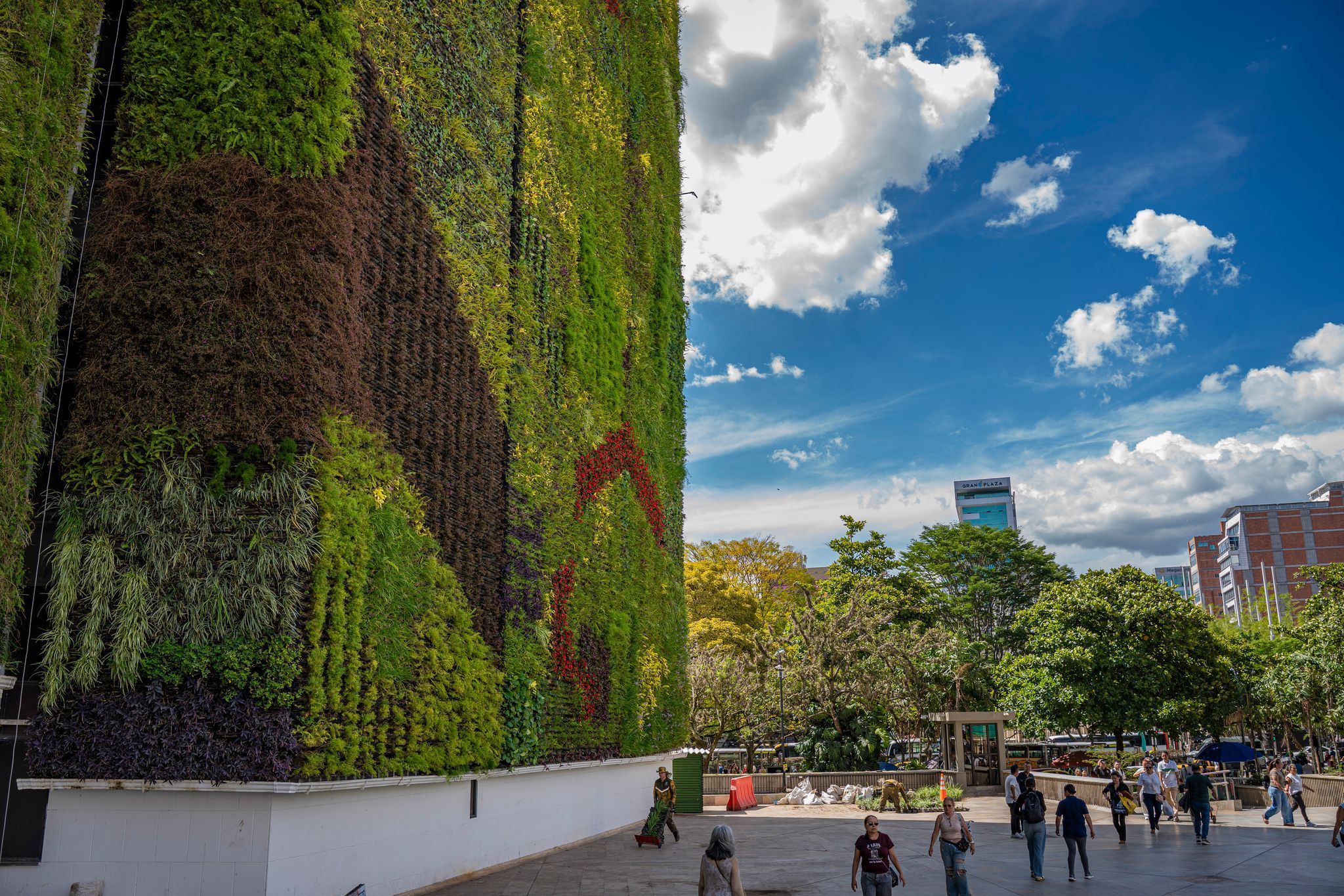 Fußgänger bewegen sich im Schatten einer begrünten Wand in Medellín. (Archivbild)