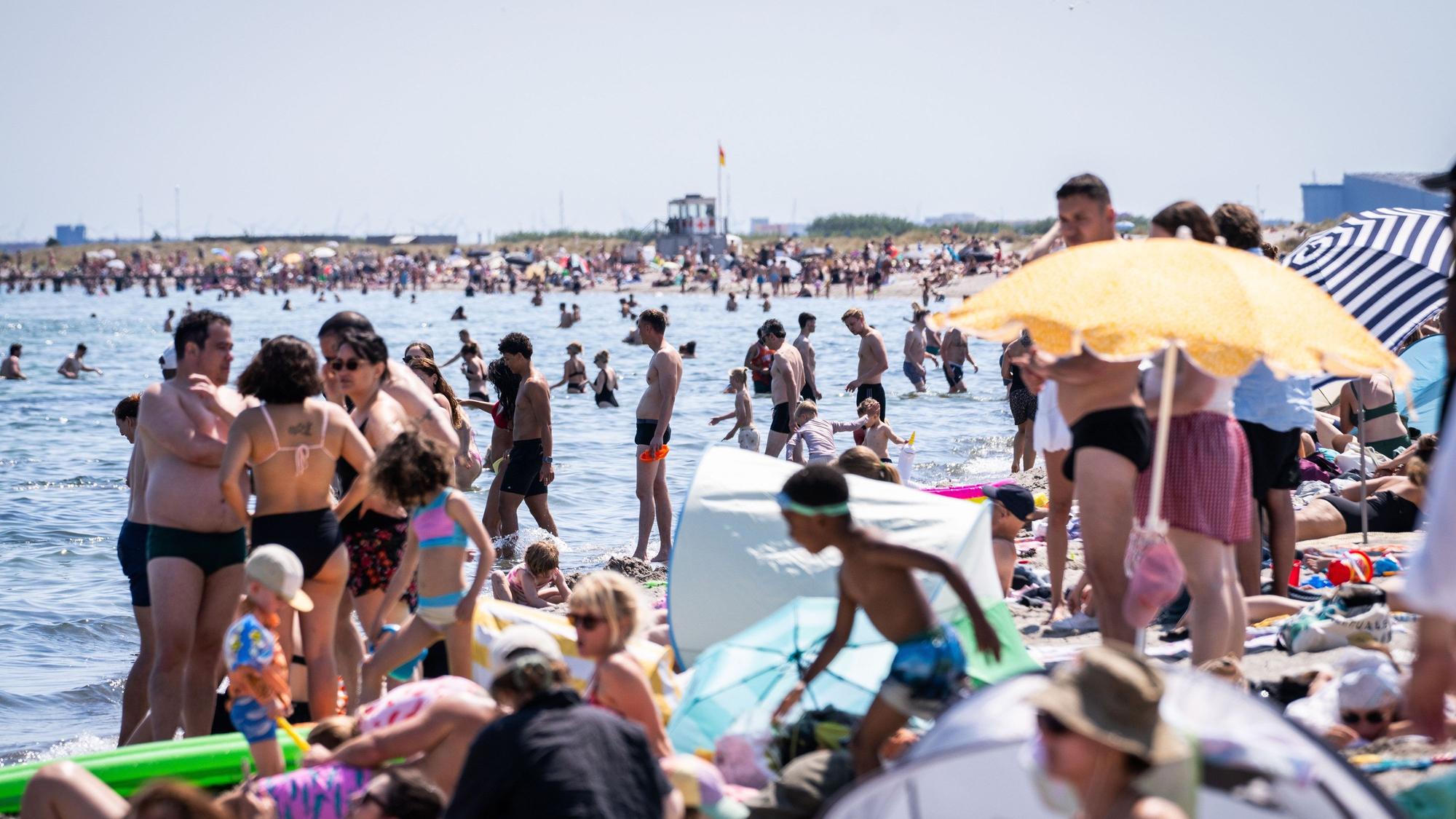 Dänemark, Kopenhagen: Menschen suchen am Amager-Strand Abkühlung im und am Wasser.