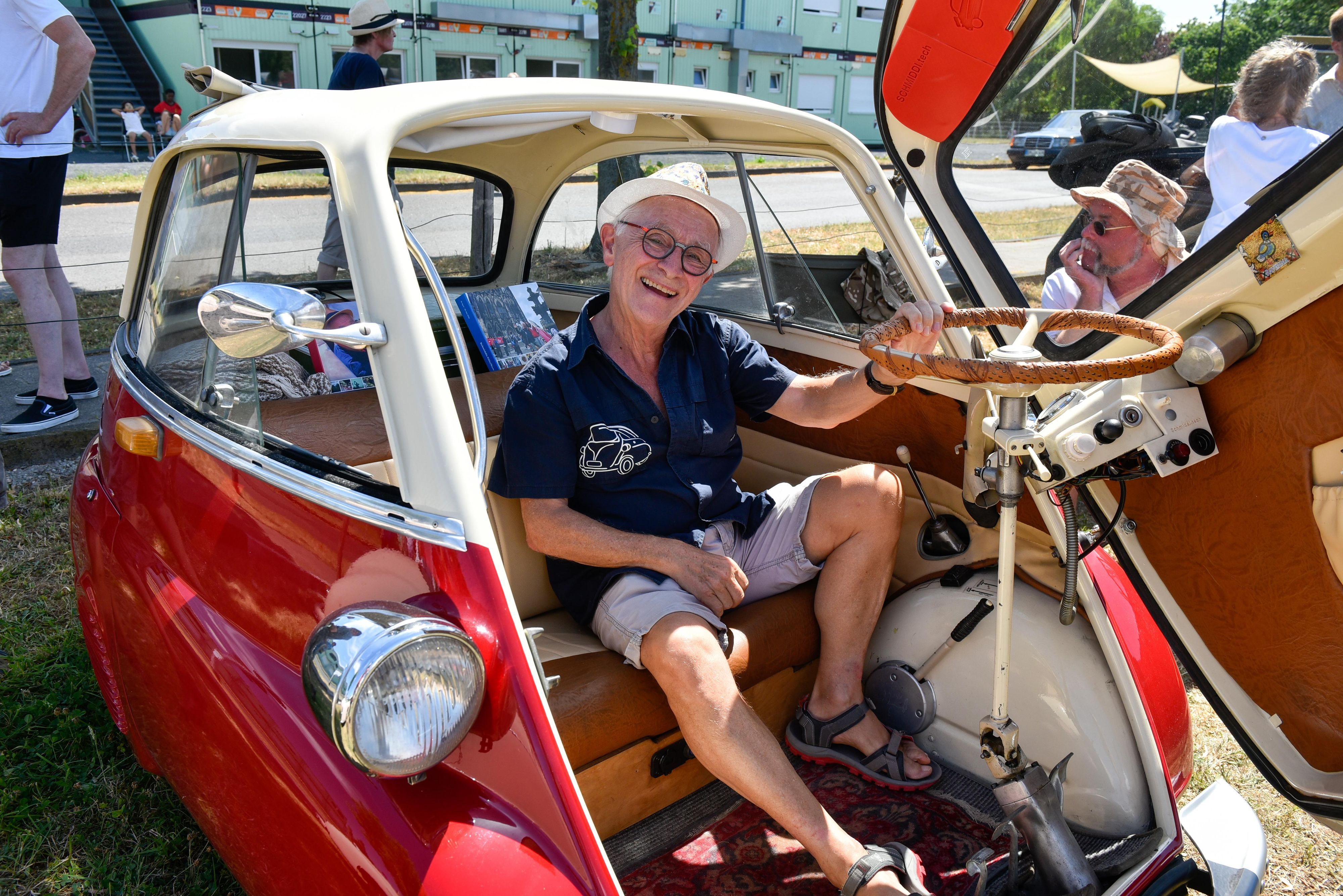 Zu sehen ist ein Mann, der in einer offenen Isetta sitzt, einem Oldtimer-Auto.