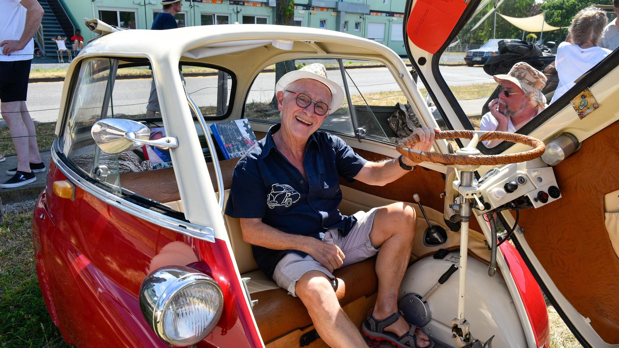 Zu sehen ist ein Mann, der in einer offenen Isetta sitzt, einem Oldtimer-Auto.