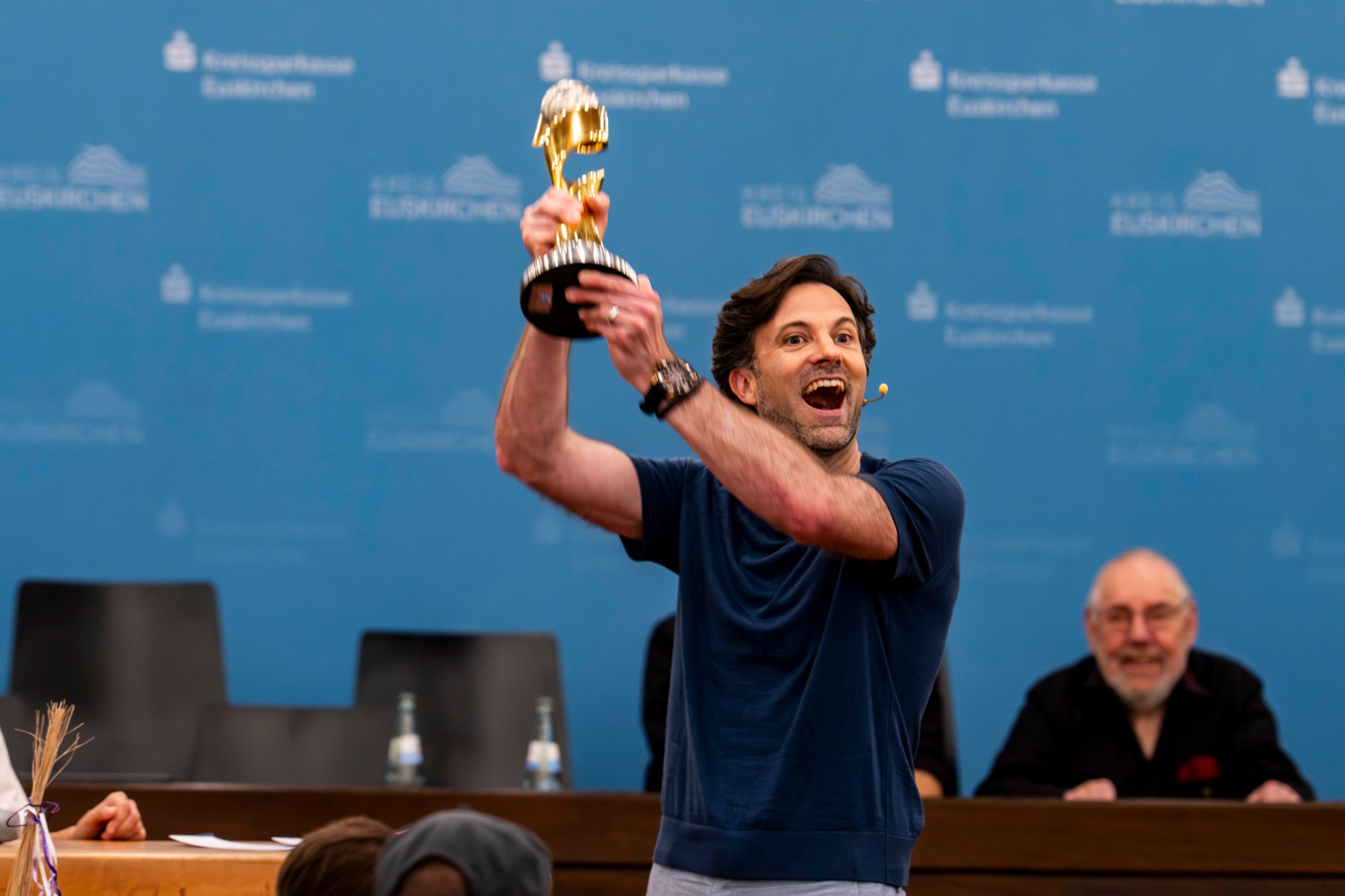 Das Bild zeigt Sebastian Tittelbach, der den Weltmeisterpokal in die Höhe reckt.