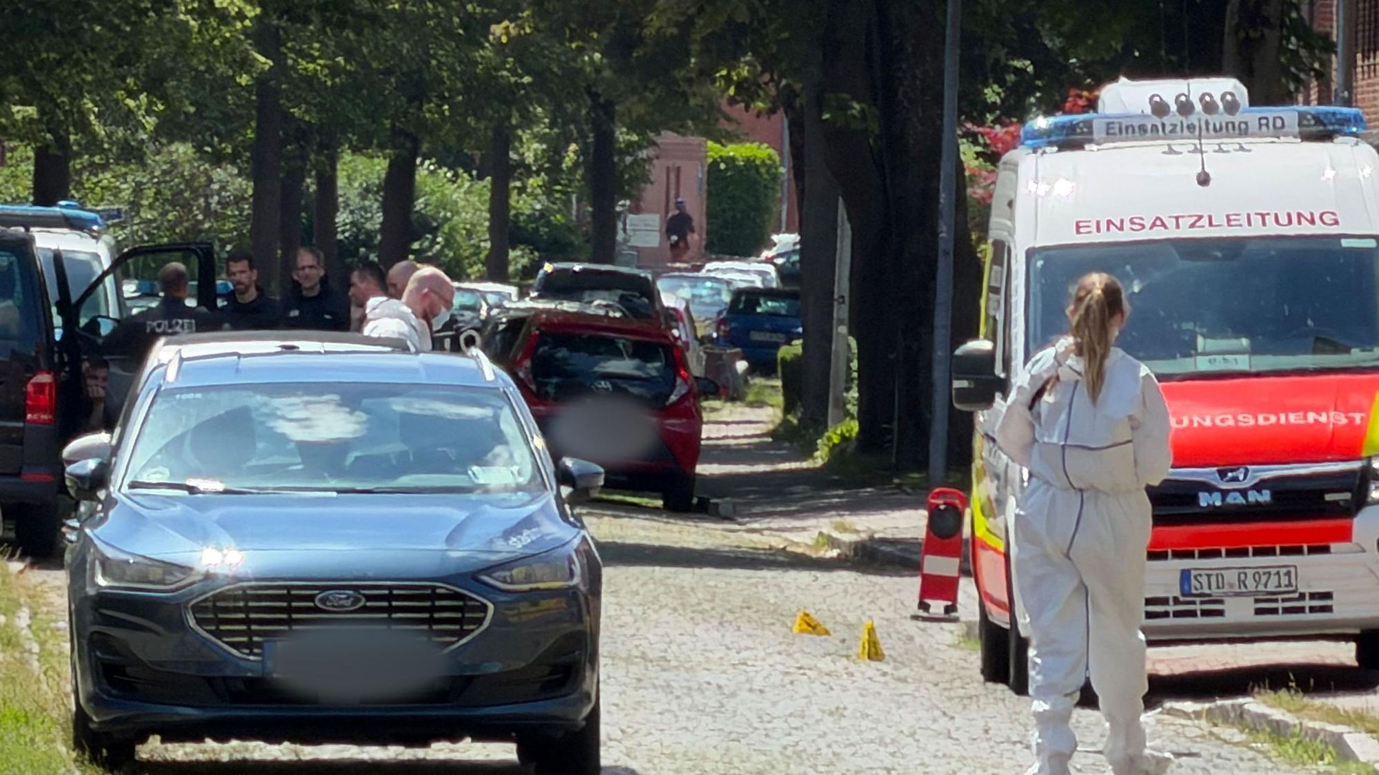 Einsatzkräfte und die Spurensicherung stehen auf einer Straße in Stade. Hier sind fünf Menschen durch Schüsse gestorben.