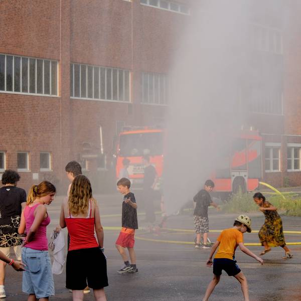 Kinder laufen durch eine Wasserfontäne.