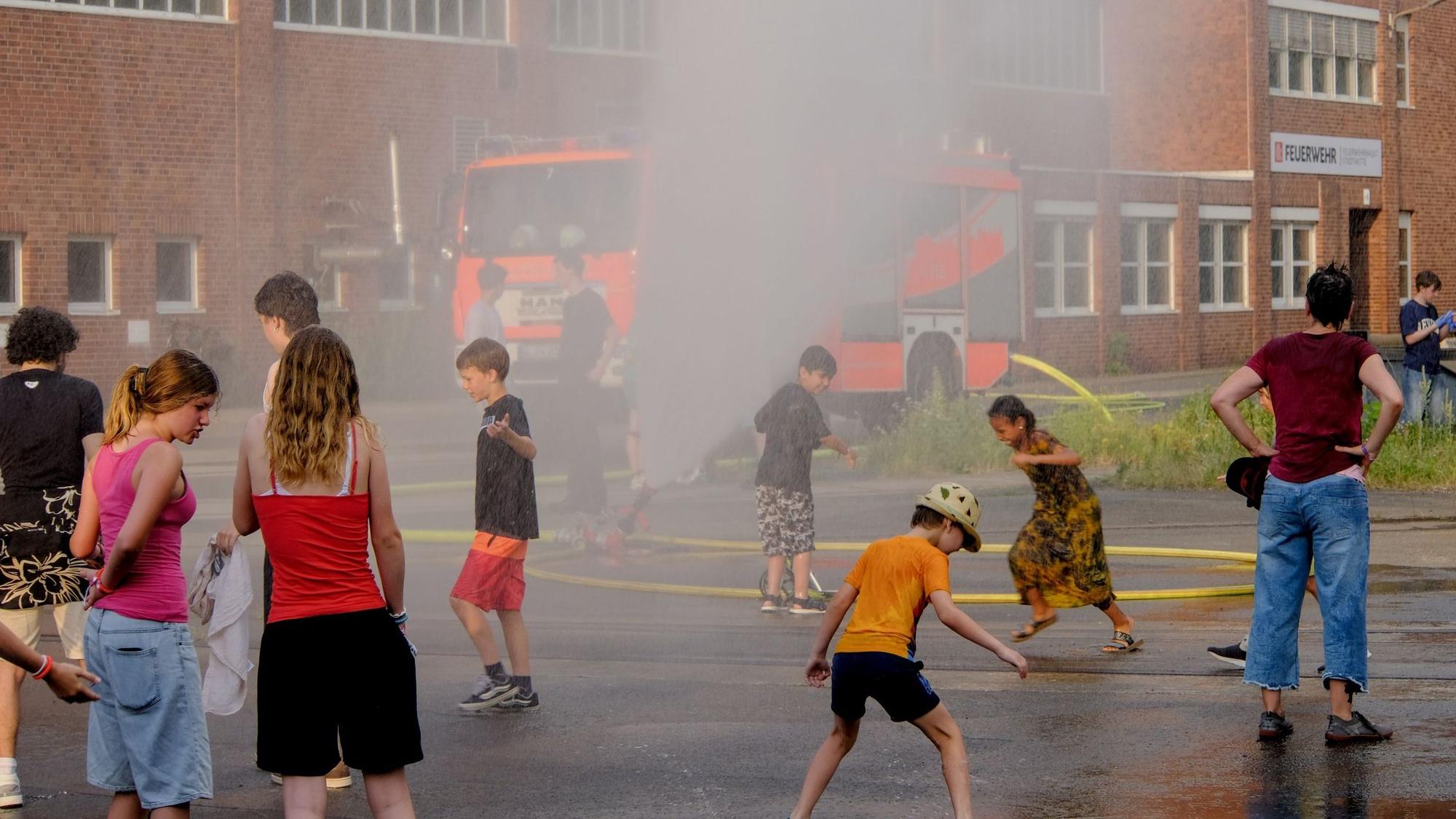 Kinder laufen durch eine Wasserfontäne.