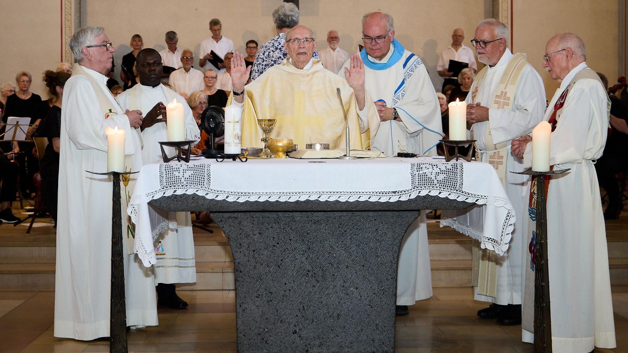 Pastor Felix Dörpinghaus (Mitte) steht mit vier weiteren katholischen Geistlichen in liturgischen Gewänddern an einem Altar.