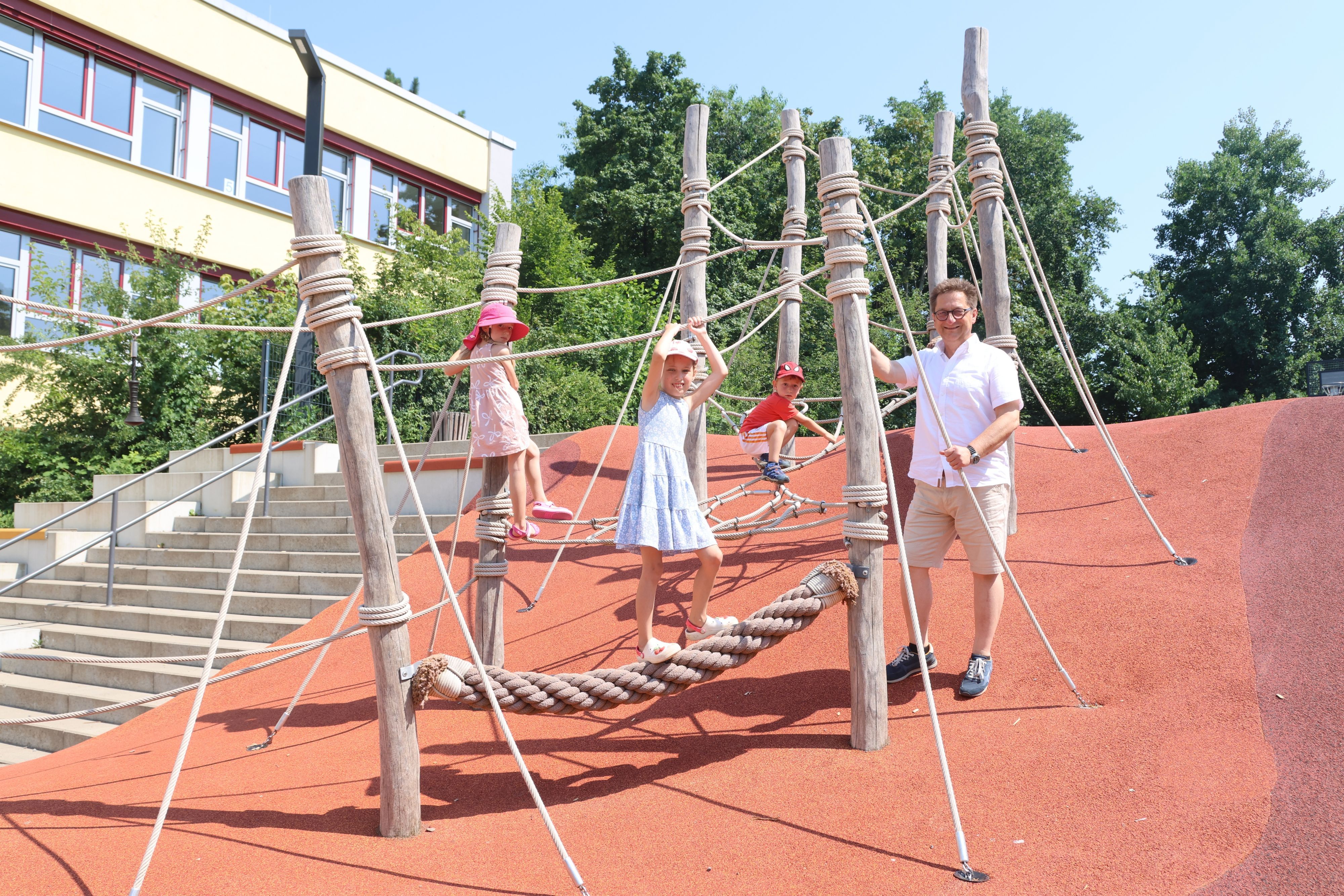 Markus Schürmann steht mit drei Kindern auf dem Schulhof der Grundschule.