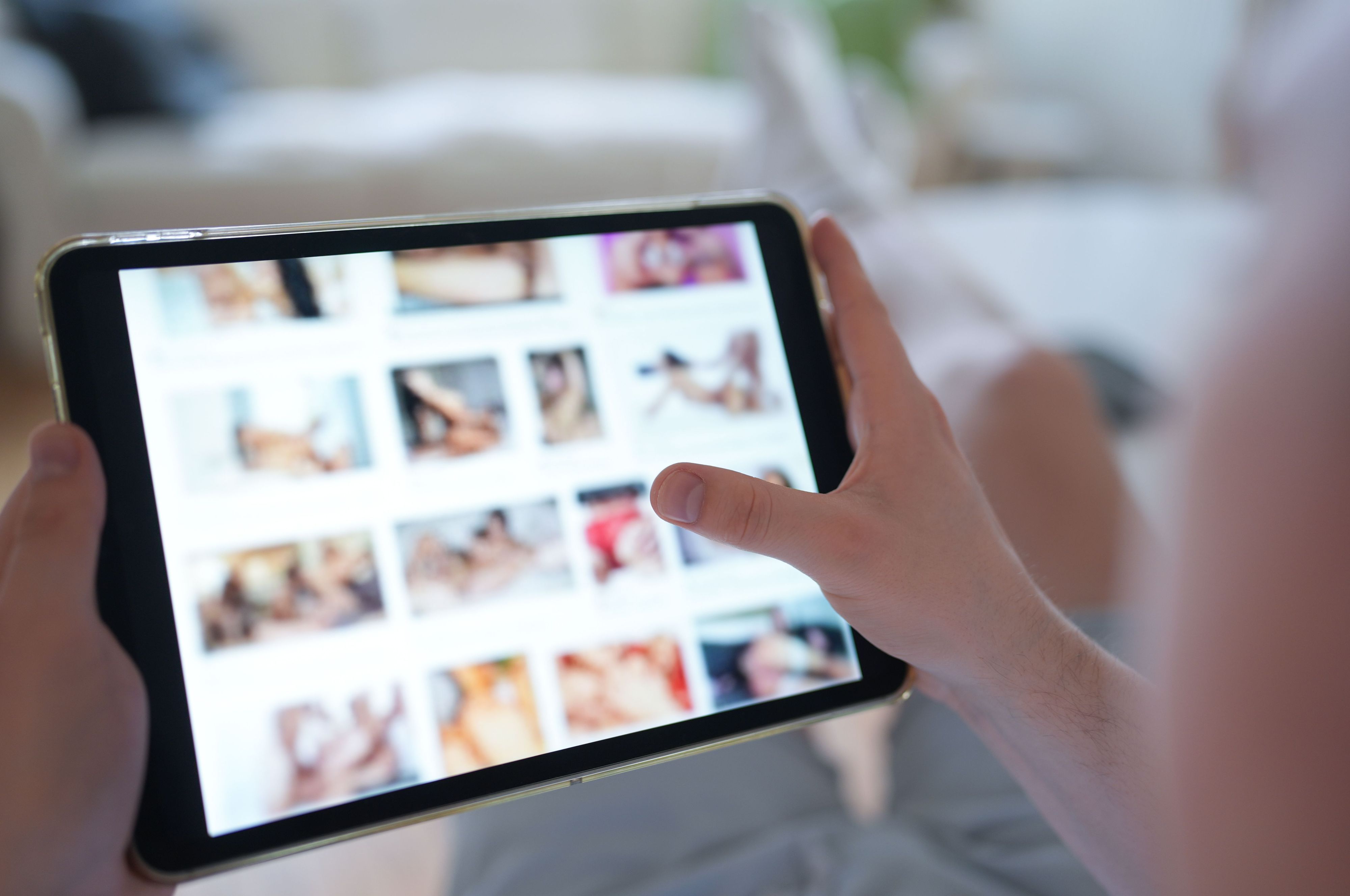 Das gestellte Foto zeigt einen Mann, der auf einen Smartphone eine Porno-Internetseite anschaut.
