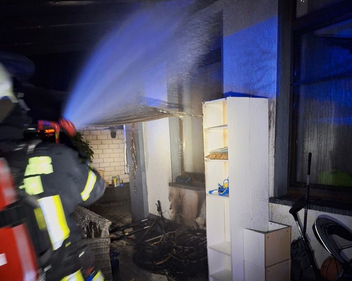 Ein Feuerwehrmann löscht einen Brand an einer Hauswand.
