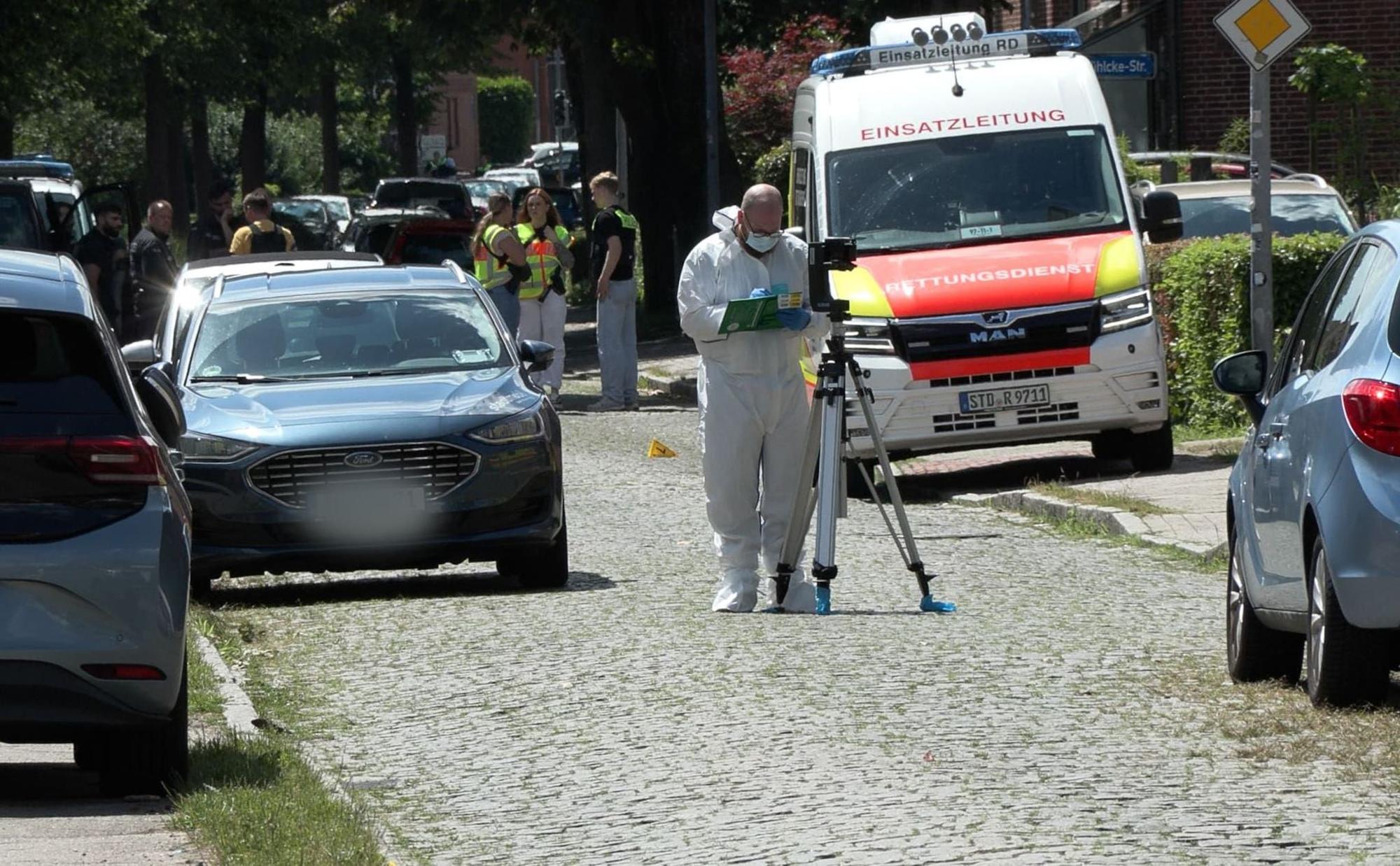 Einsatzkräfte und Spurensicherung stehen nach der Bluttat in Stade auf einer Straße.