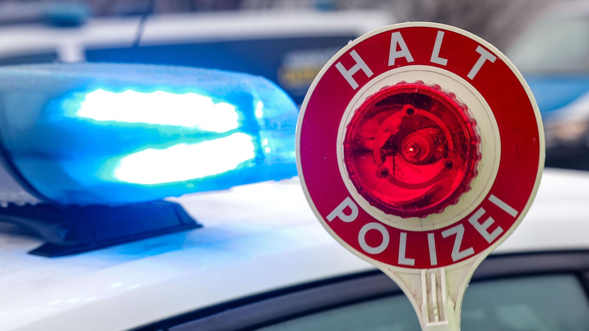 Ein Polizist hält eine Polizeikelle für eine Kontrolle auf einem Parkplatz an der Autobahn.