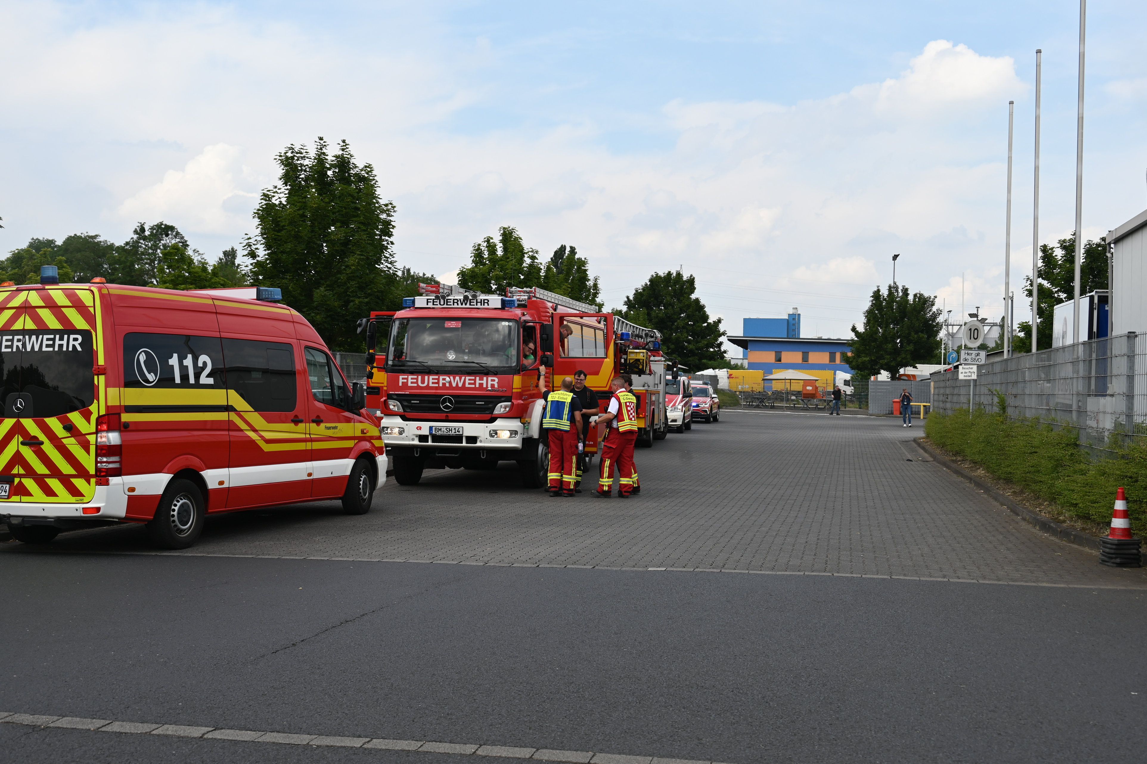 Vor der Einfahrt zur Firma stehen mehrere Feuerwehrfahrzeuge.