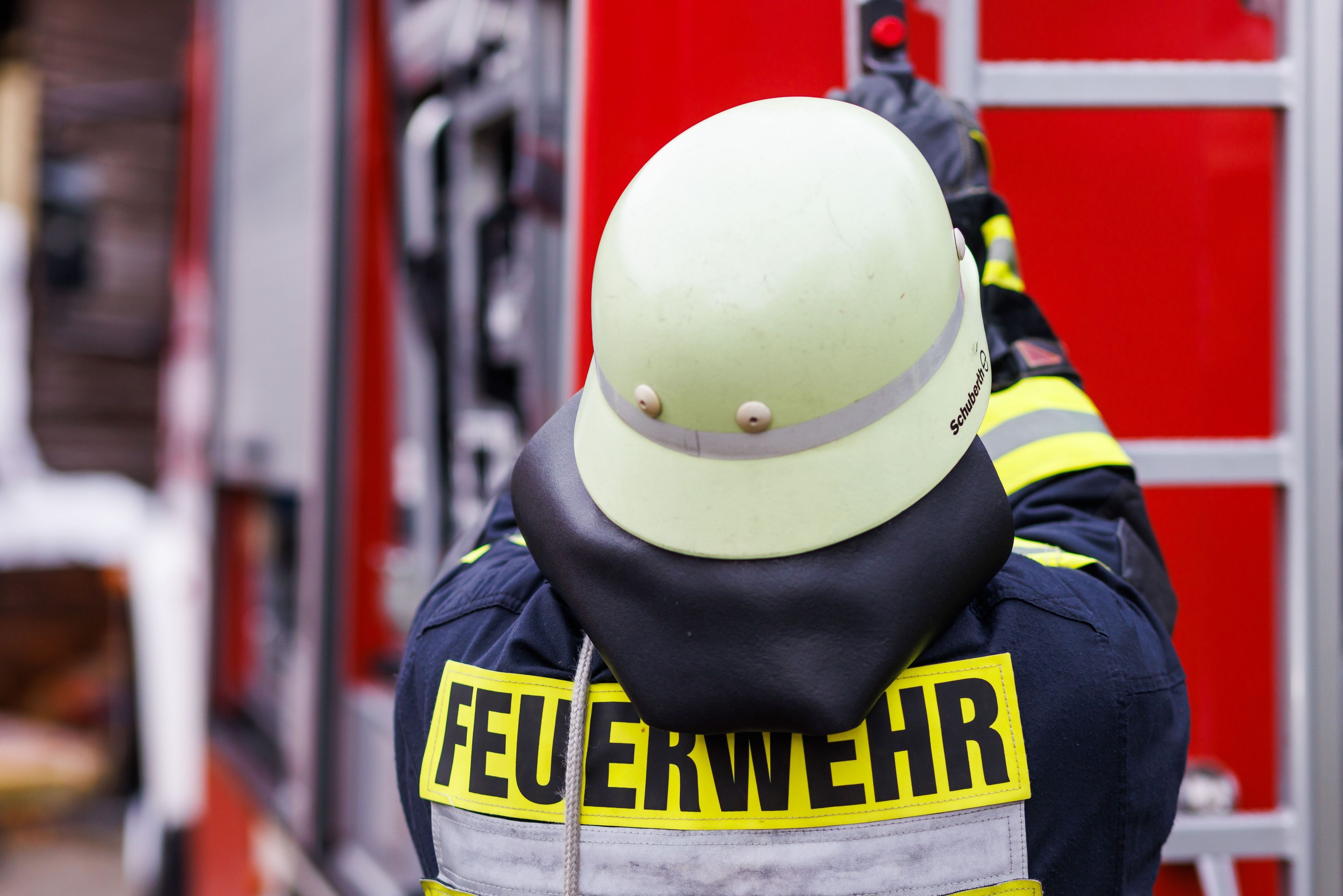 Ein Feuerwehrmann holt während einer Einsatzübung einer Freiwilligen Feuerwehr eine Leiter vom Dach eines Einsatzfahrzeugs.