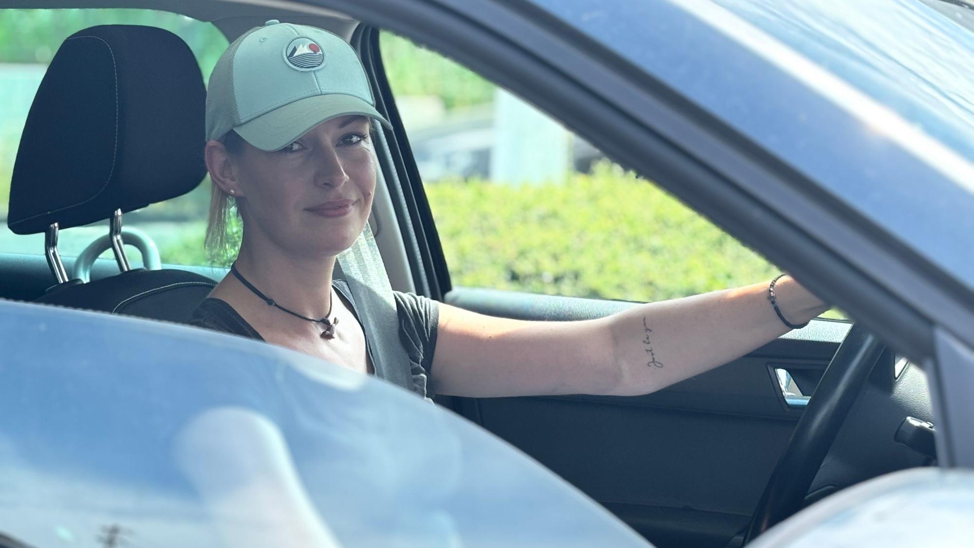 Inga G. sitzt in ihrem Auto während sie auf eine freie Tanksäule wartet.