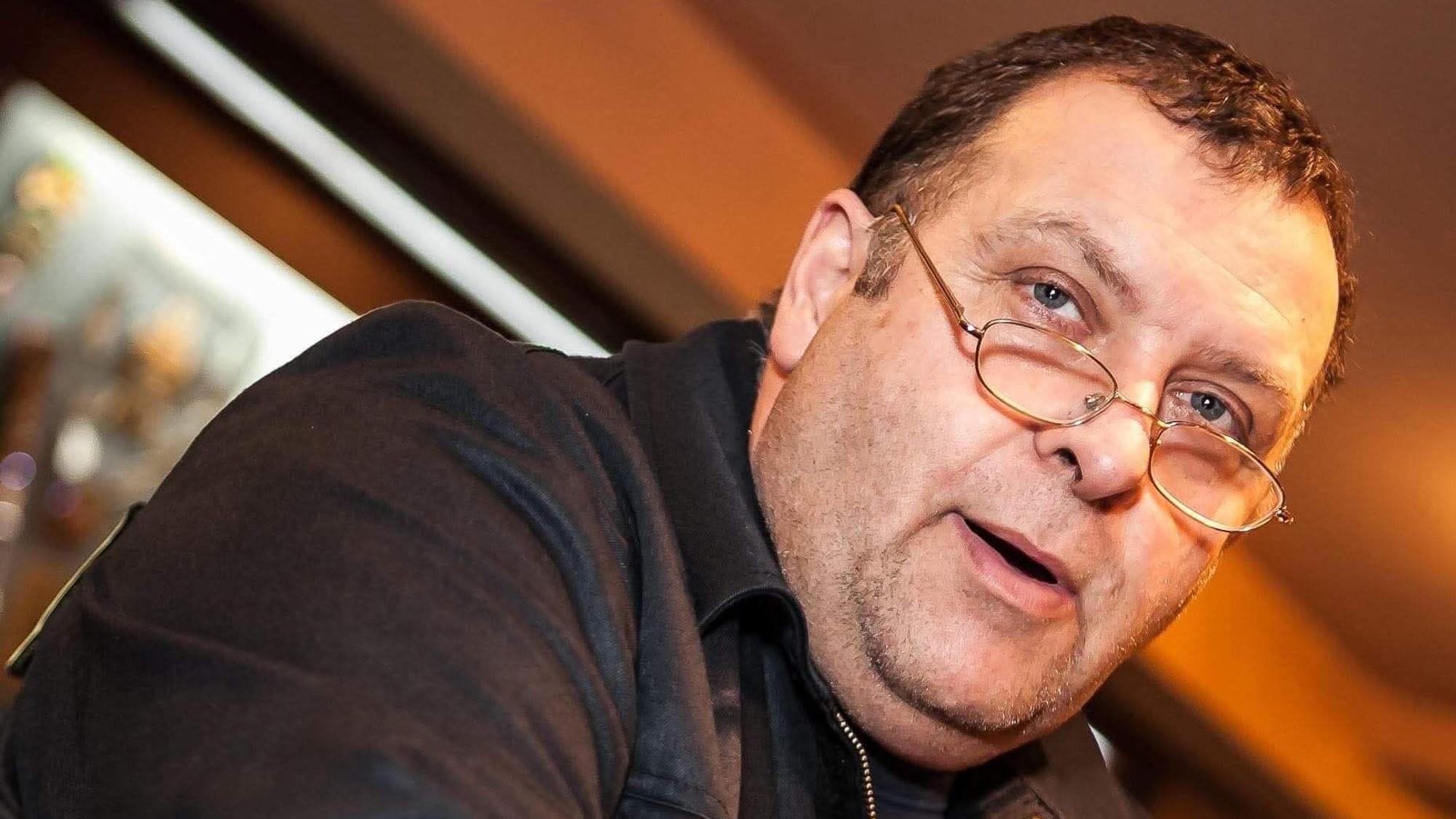 Ein Mann mit Brille befindet sich in einem Raum.