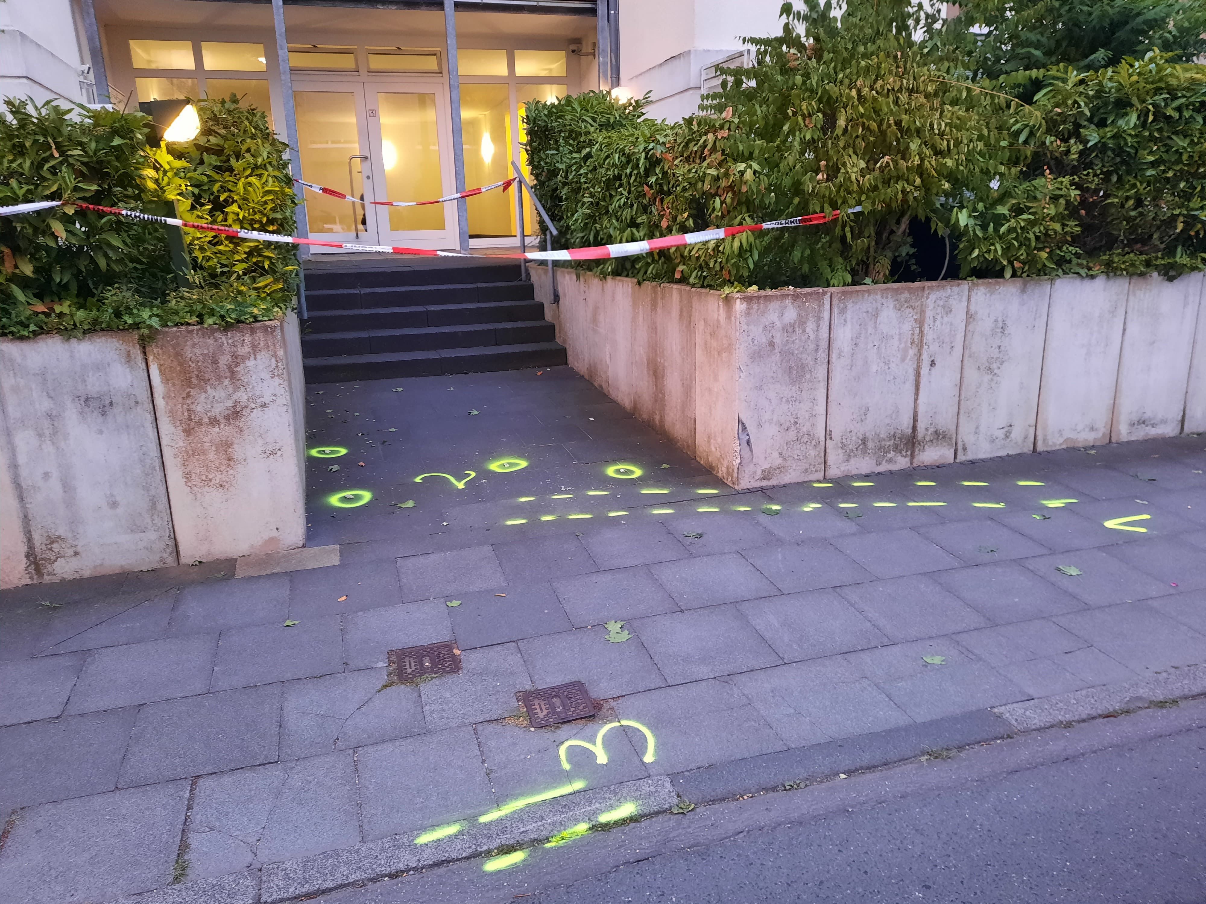 Markierungen der Poliziei auf dem Gehweg, im Hintergrund der Eingang zu einem Haus.
