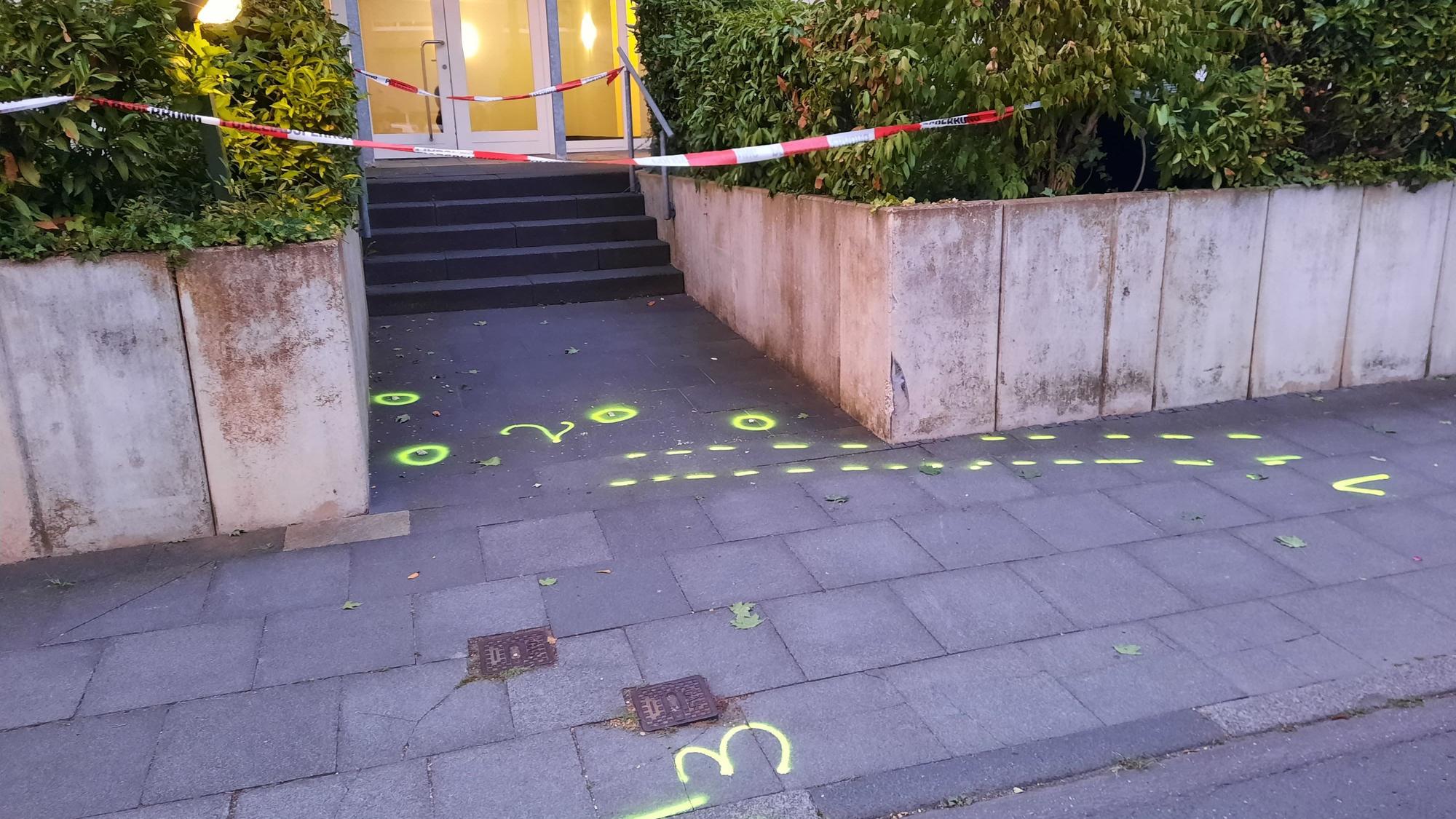 Markierungen der Poliziei auf dem Gehweg, im Hintergrund der Eingang zu einem Haus.