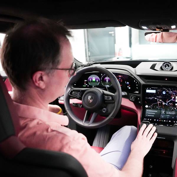 Ein Mann sitzt hinter dem Steuer eines Sportwagens und schaut auf das große Digital-Display neben dem Lenkrad.