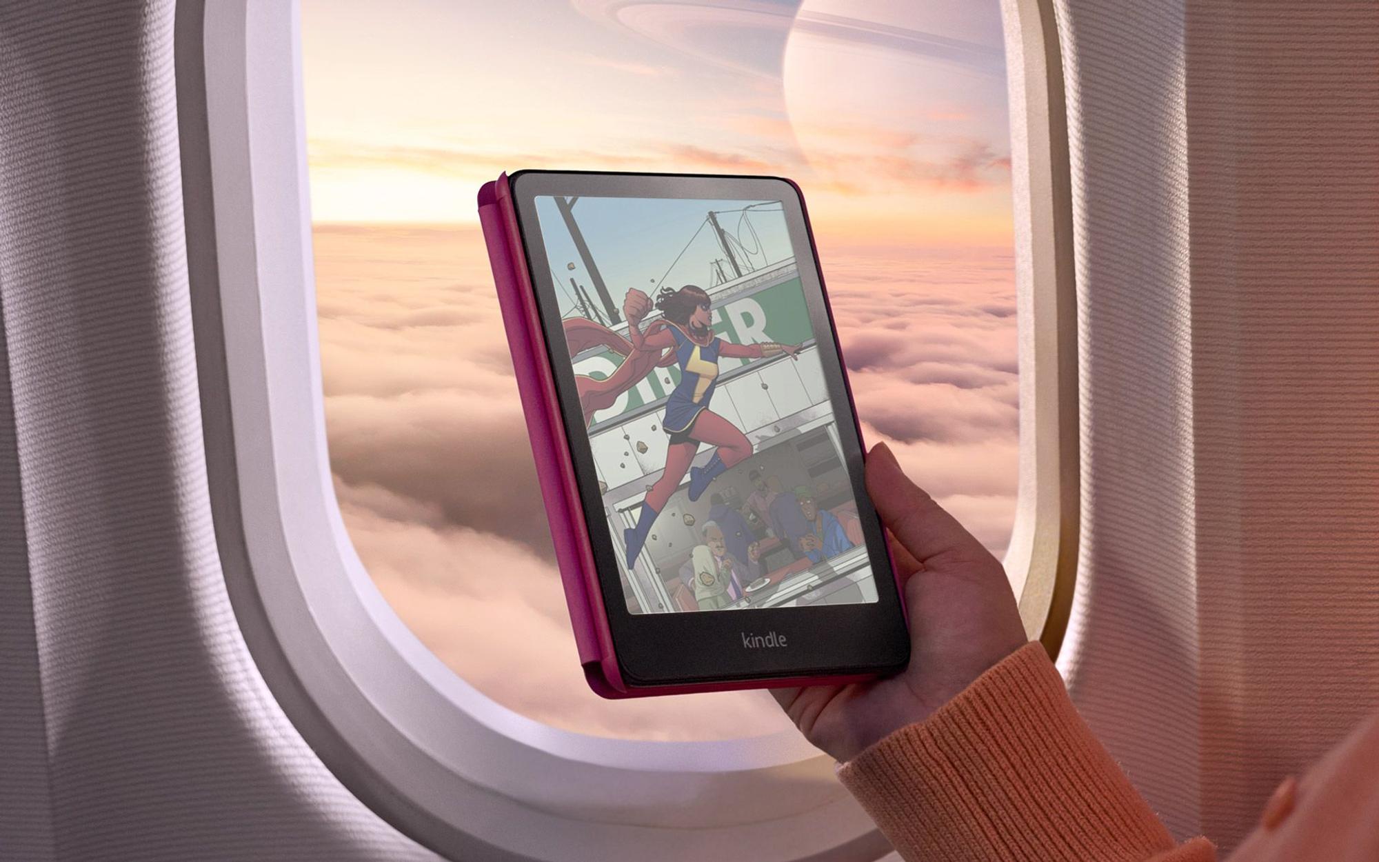 Amazon Kindle Colorsoft Signature Edition in einer Hand vor einem Flugzeugfenster, auf dem Display eine farbige Comic-Szene mit einer Superheldin.