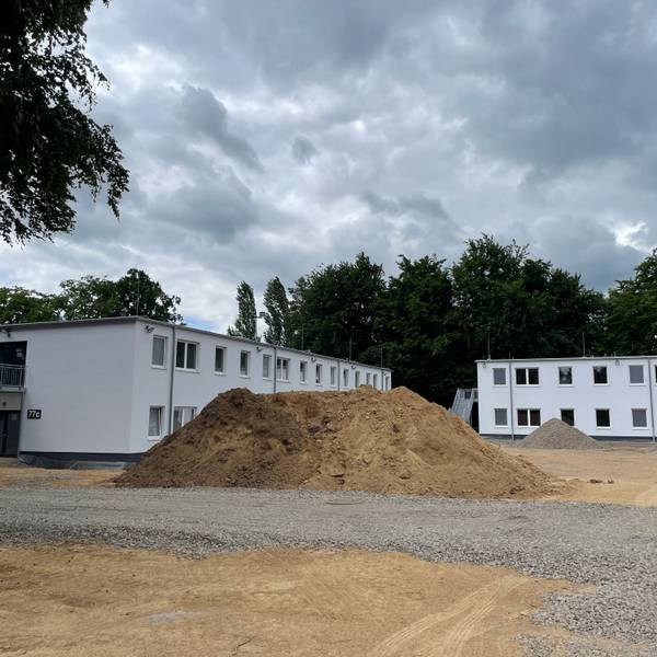 Zwei Gebäudekörper mit weißer Fassade.