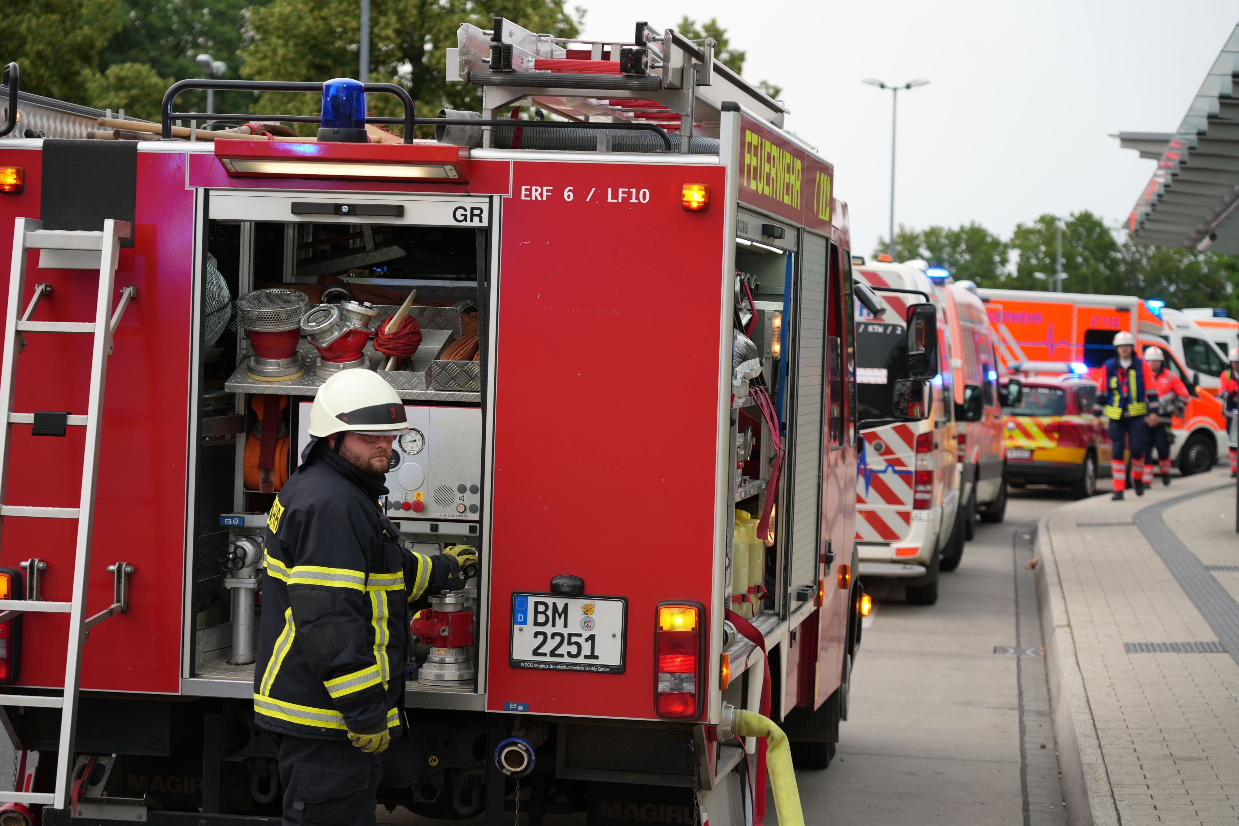 Löschfahrzeuge, Rettungswagen, ein Notarztfahrzeug und Krankentransportfahrzeuge stehen an einer Straße.