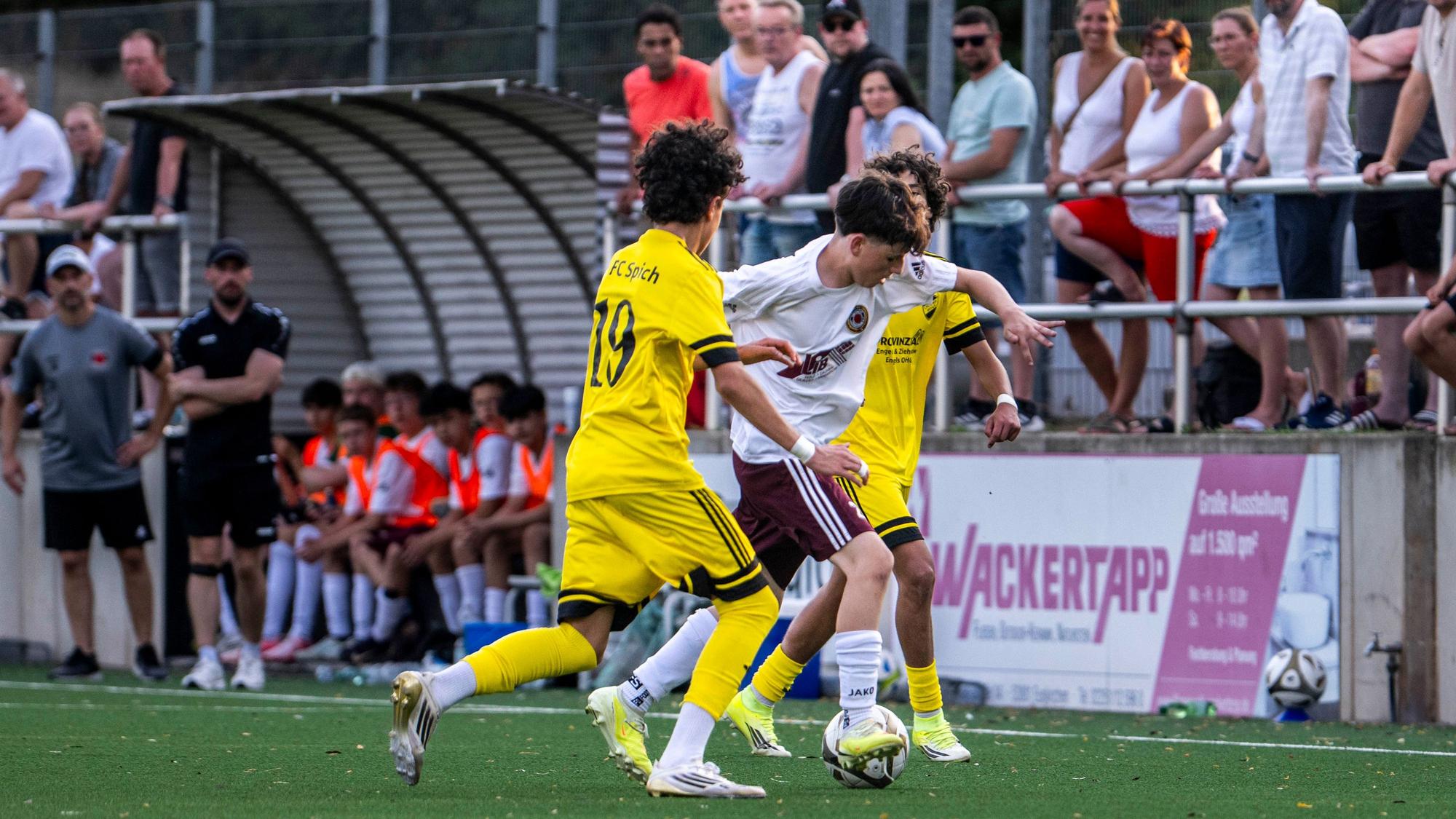 Ein Spieler des SSV Lommersum dribbelt gegen zwei Gegenspieler.
