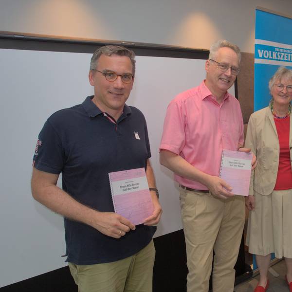 Drei Männer und eine Frau zeigen ein Buch.