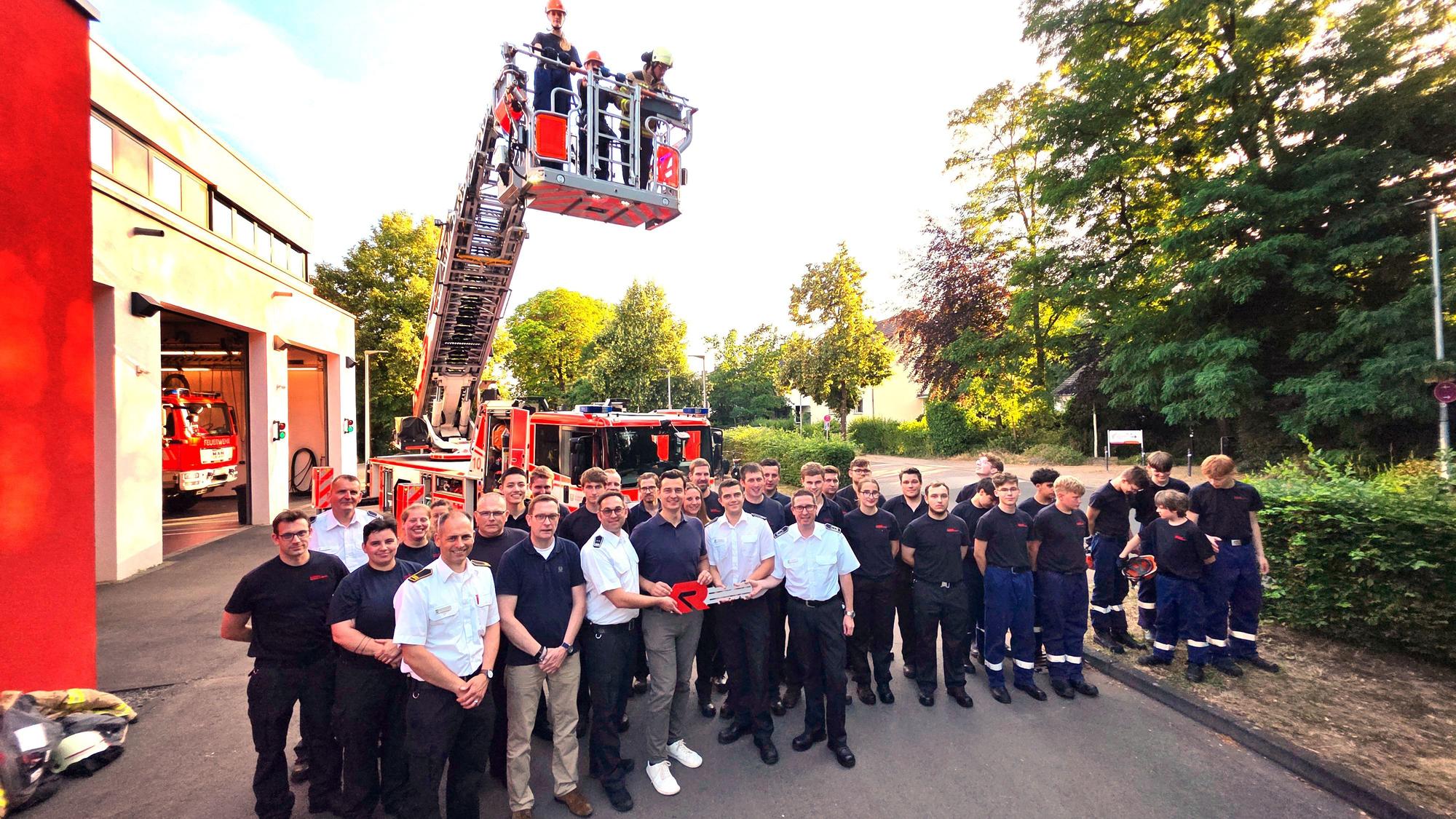 Feuerwehrleute und Vertreter der Stadt Bergisch Gladbach stehen vor der neu in Dienst gestellten Drehleiter in Bergisch Gladbach-Refrath.