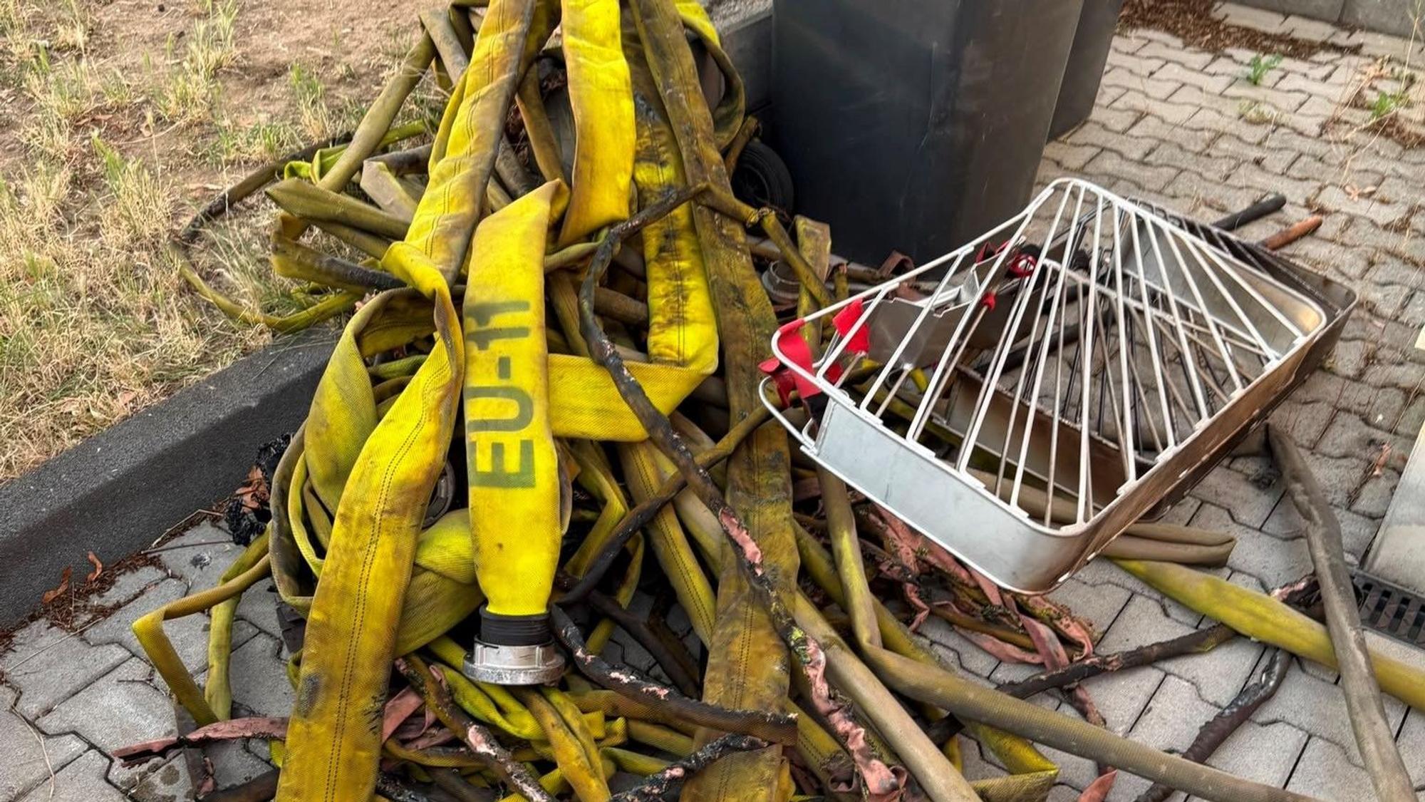 Angeschmorte Feuerwehrschläuche liegen auf einem Haufen.