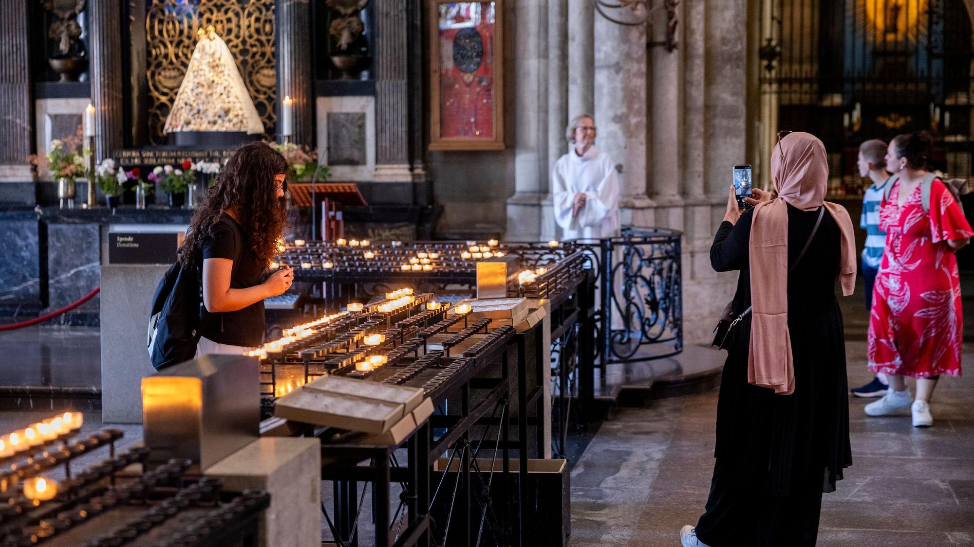 Eine Frau (r.) fotografiert die Schmuckmadonna im Kölner Dom.